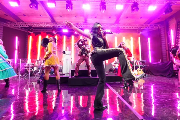 singers on stage in fringe clothing with pink lighting