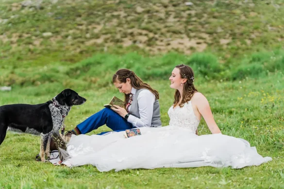 brides write their wedding vows by a lake while dog waits patiently