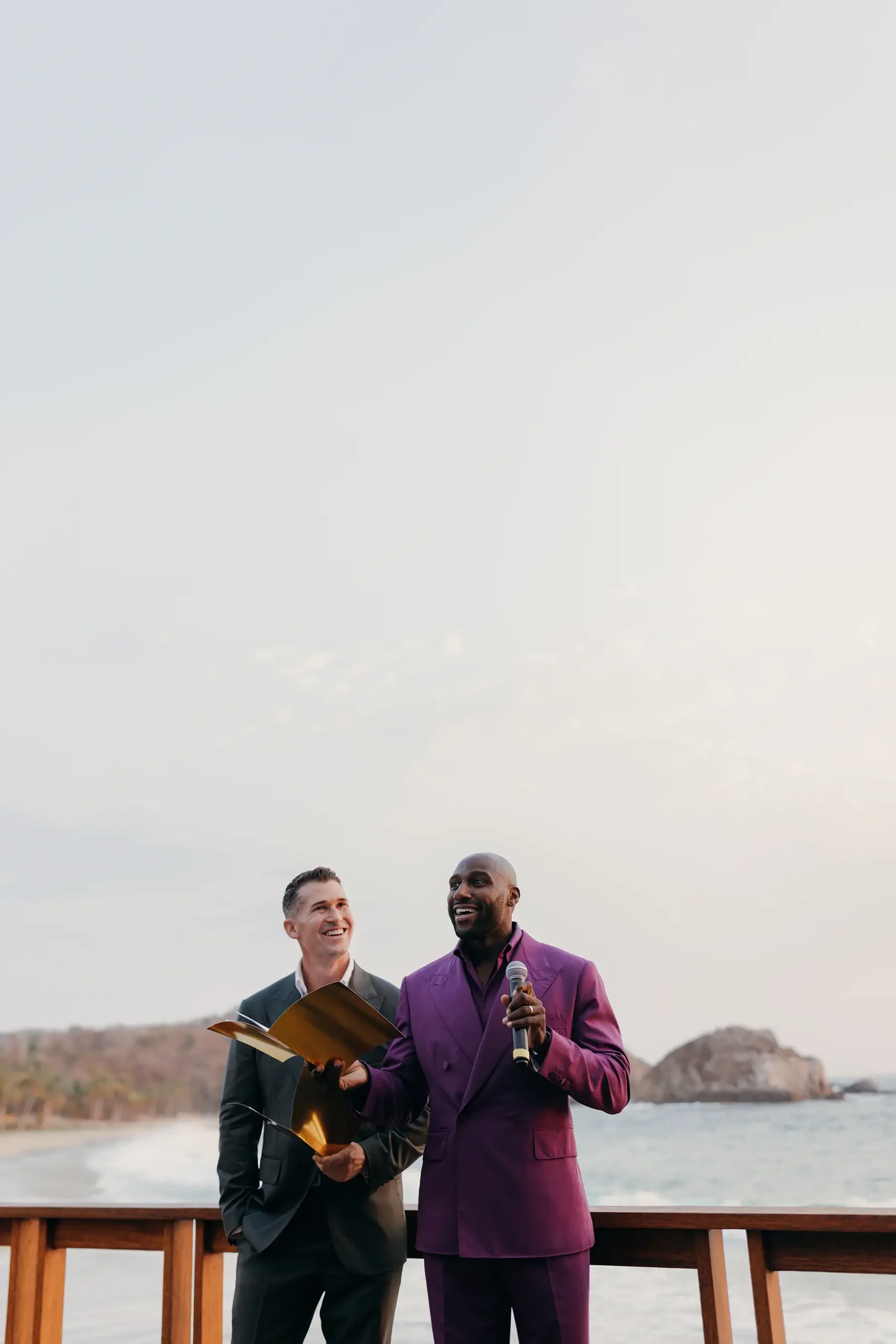 Two grooms in purple and olive green Michael Andrews Bespoke suits at their Four Seasons Tamarindo welcome party in Mexico