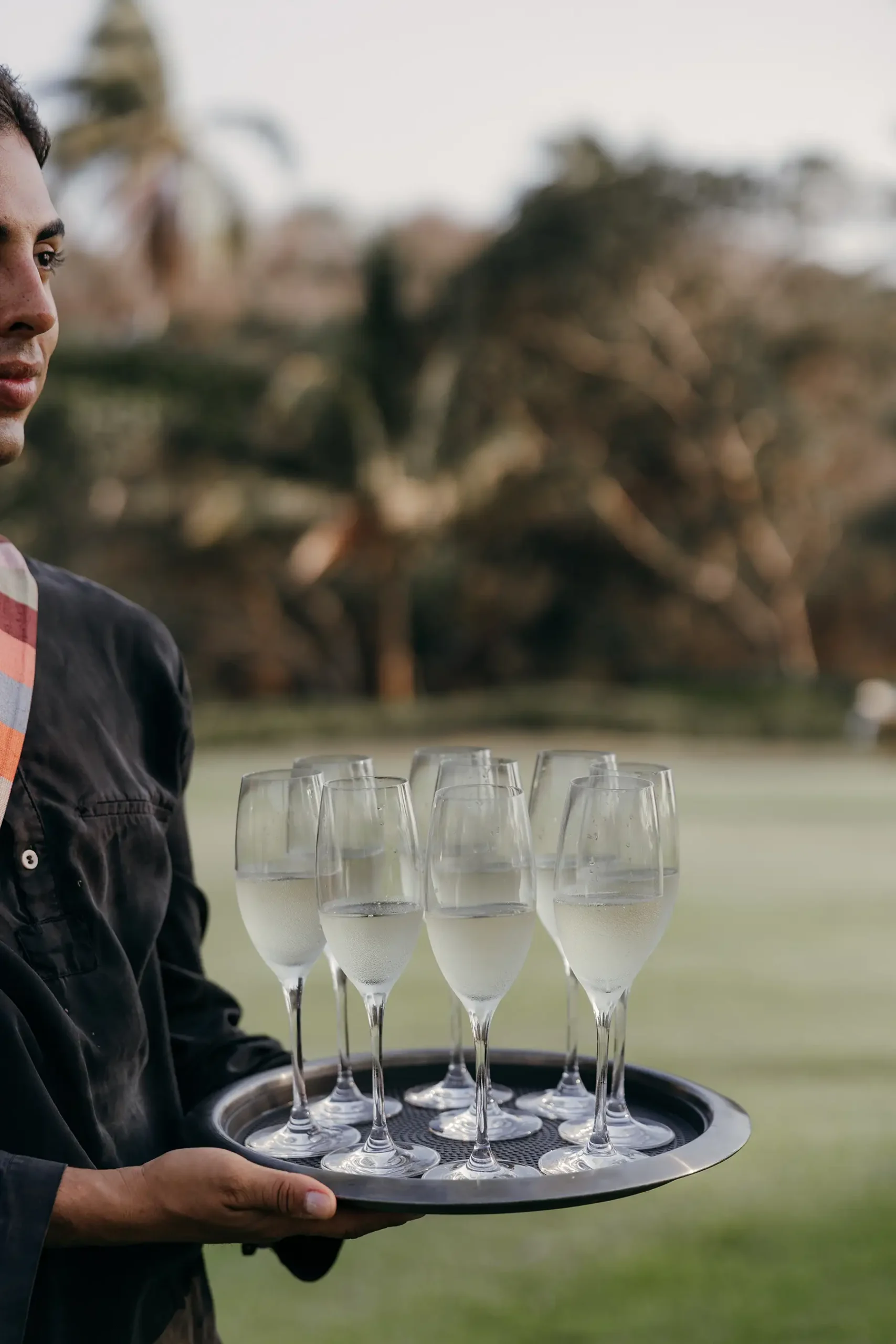 Waiter with filled glasses for wedding guests at destination wedding