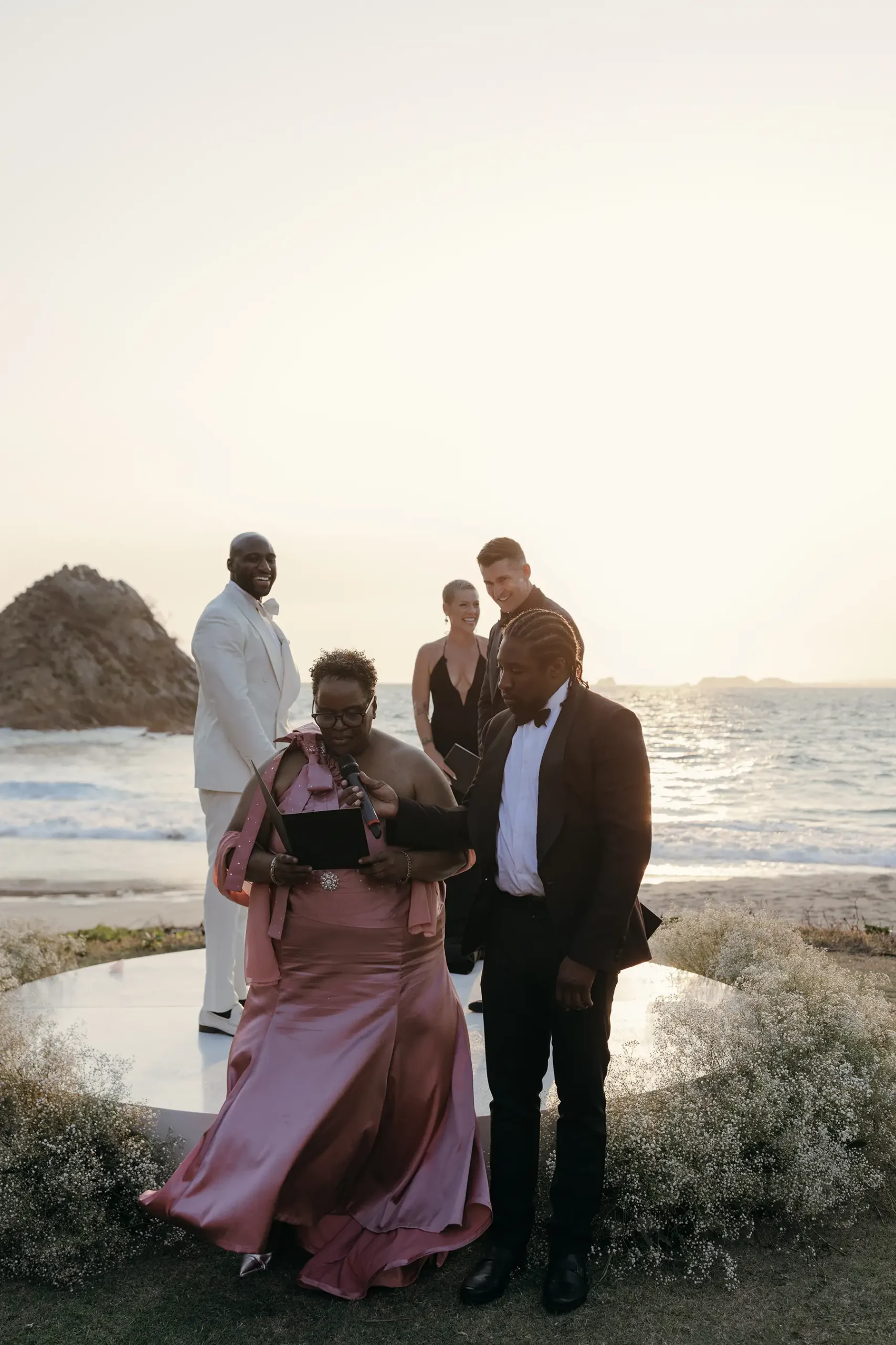 hasan Brailsford and Jason Silverman with P!nk officiating on white platform with baby's breath and ocean at Four Seasons Tamarindo
