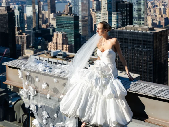 Model bride sits atop building in New York City modeling Ese Azenabor wedding gown and veil
