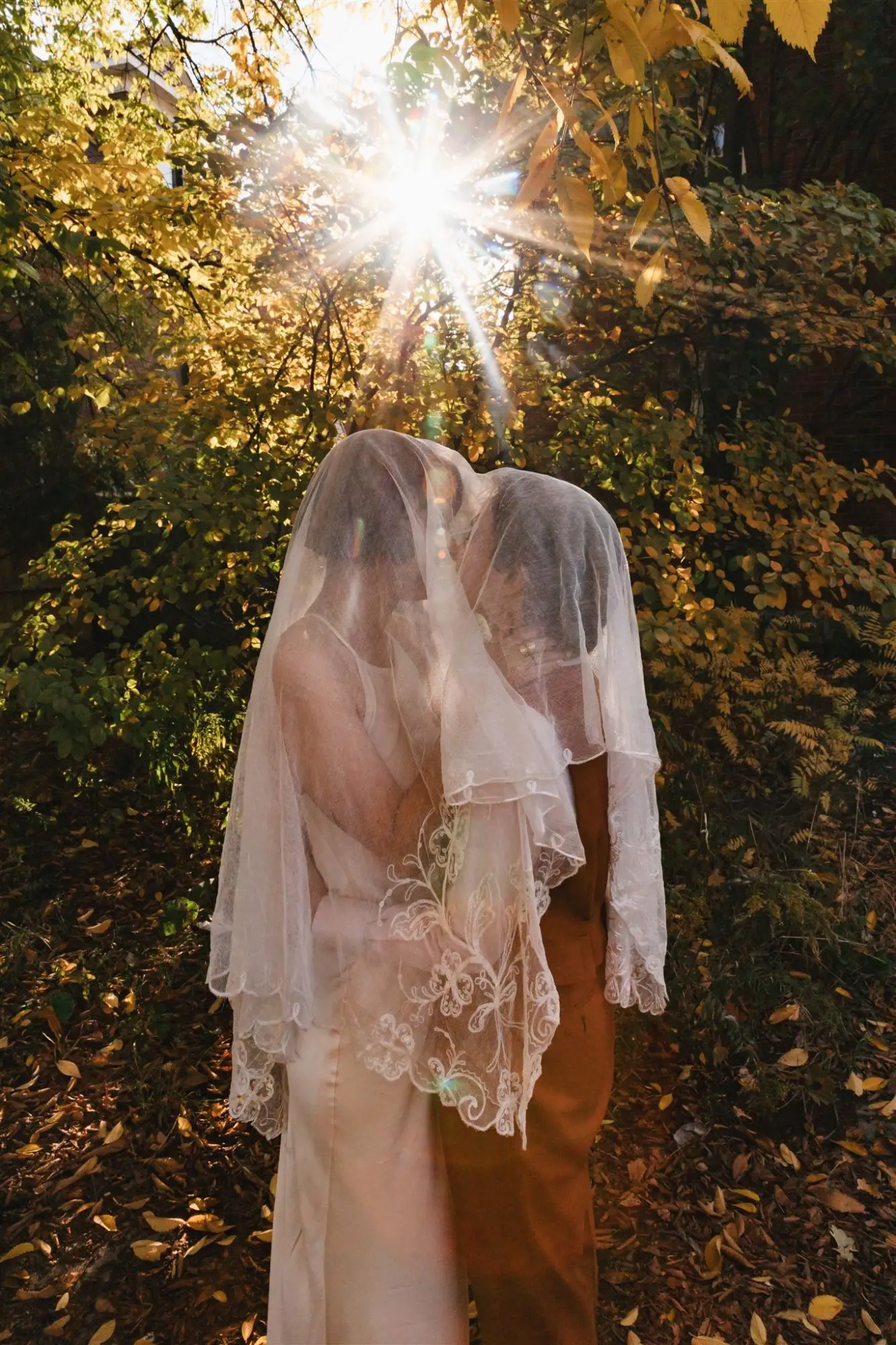 Queer wedding couple kissing under veil