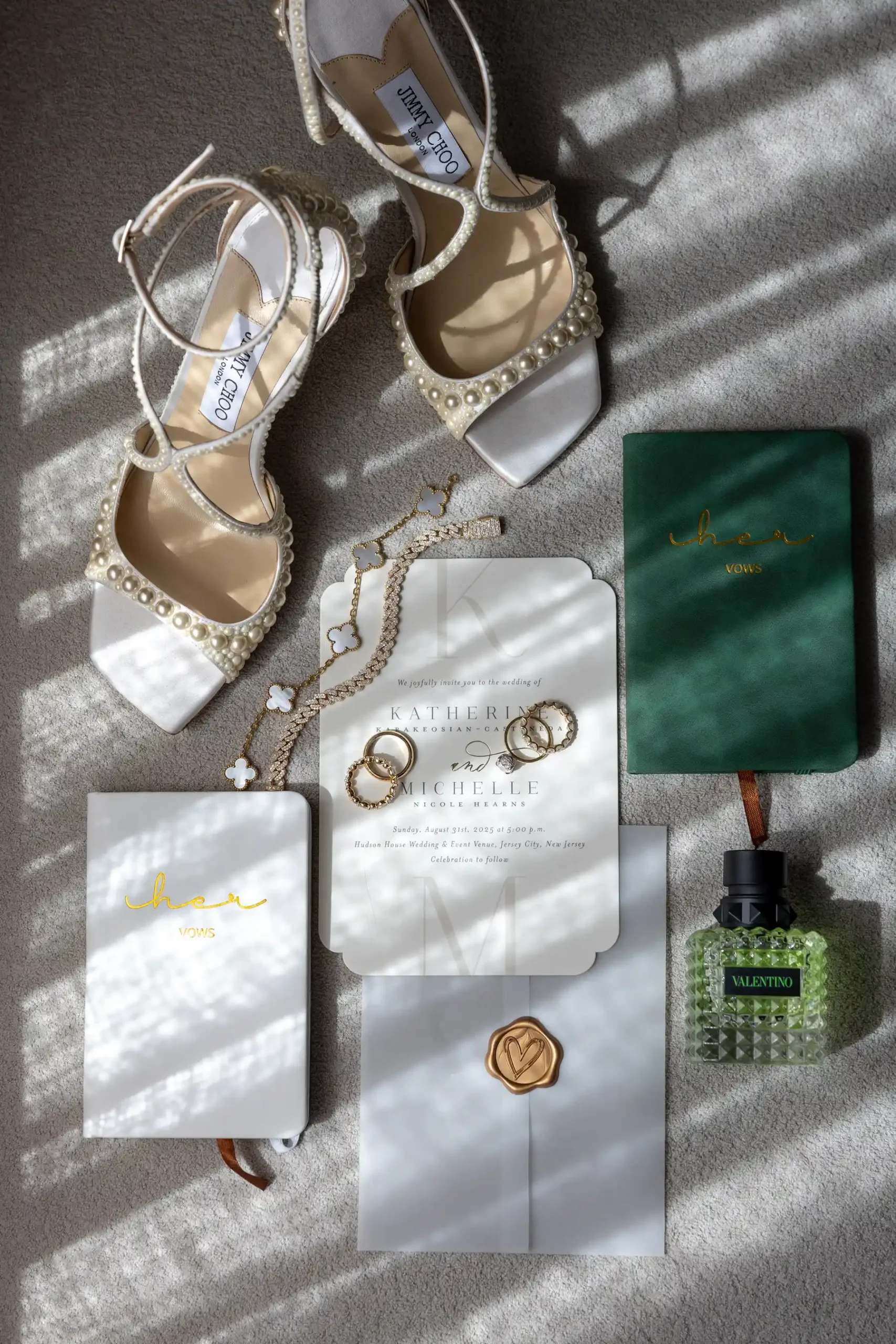 Wedding flat lay for Katherine and Michelle at Hudson House featuring Jimmy Choo pearl heels, vow books, and Valentino perfume.