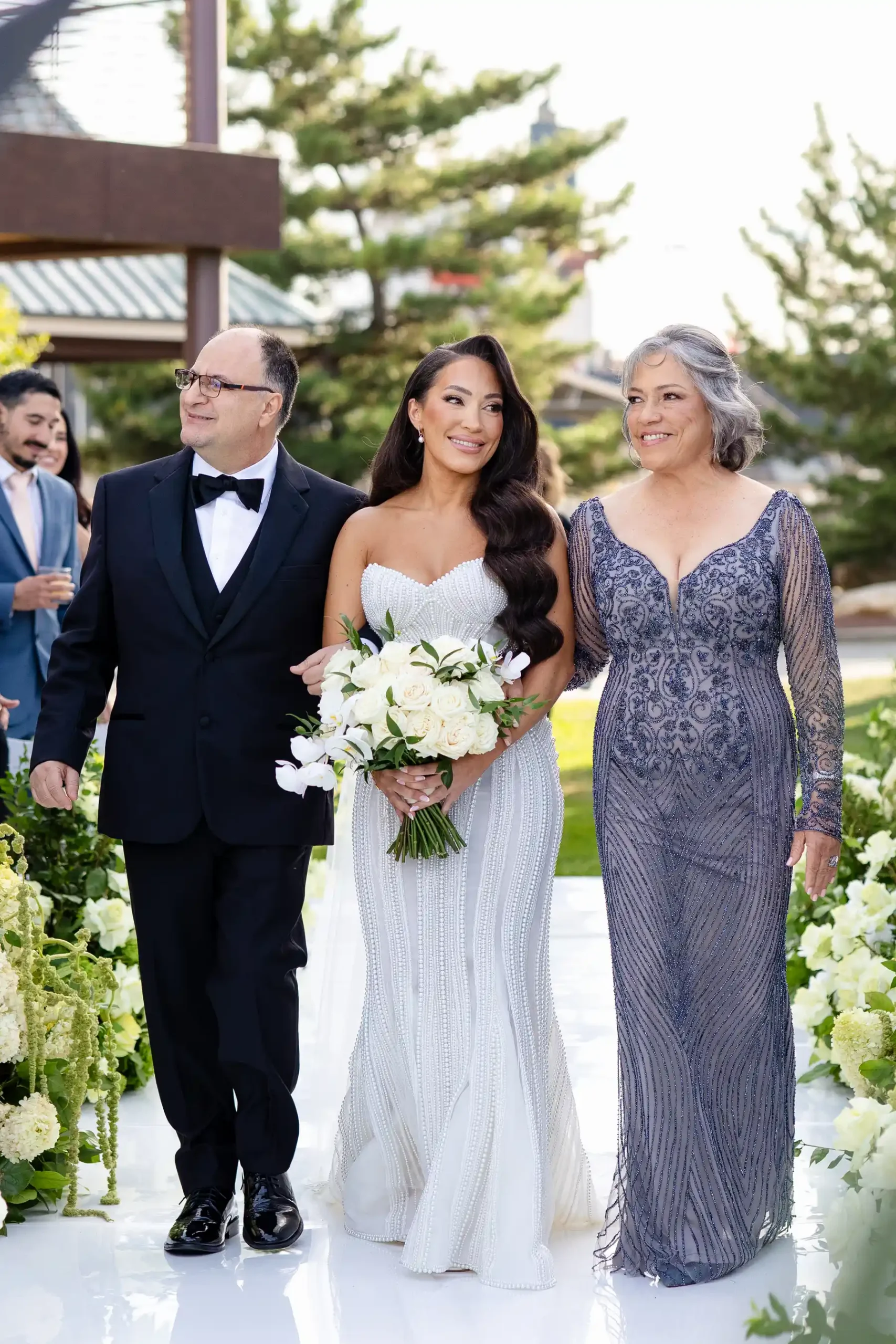 Bride Katherine walks the aisle at Hudson House in Jersey City flanked by two smiling family members.