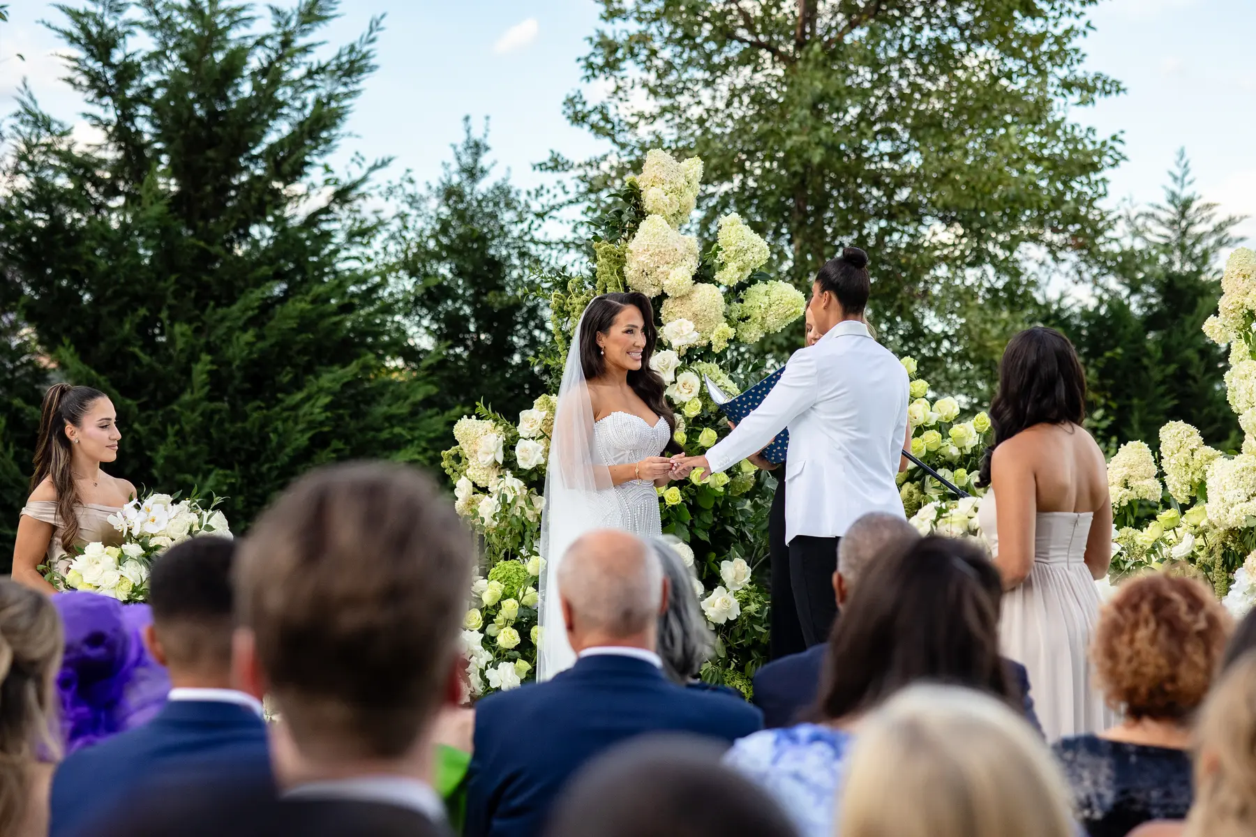 Katherine and Michelle exchange vows at their outdoor ceremony at Hudson House in Jersey City, surrounded by white hydrangeas.
