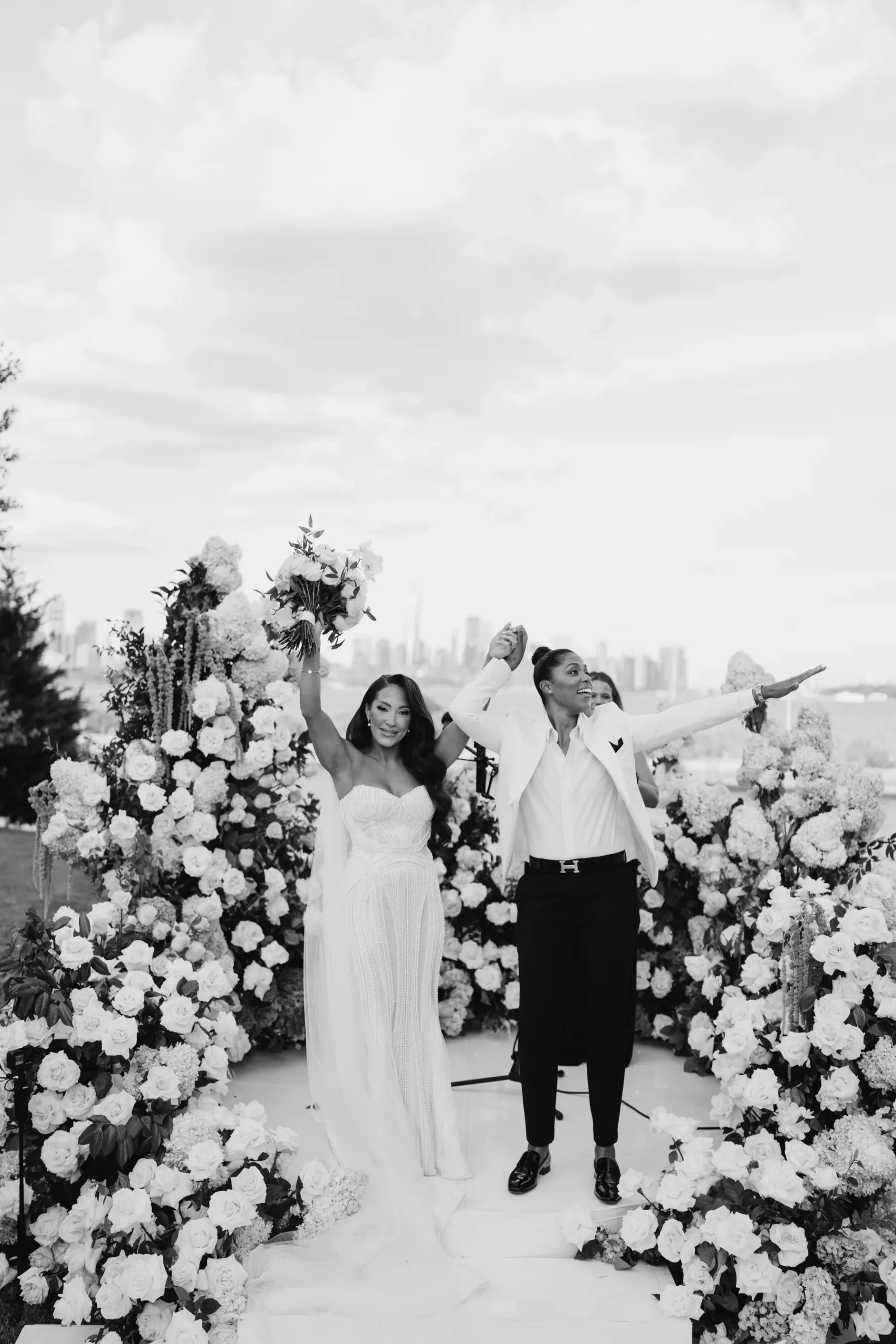 Katherine and Michelle celebrate as newlyweds amid white floral arches at Hudson House in Jersey City, N.J.