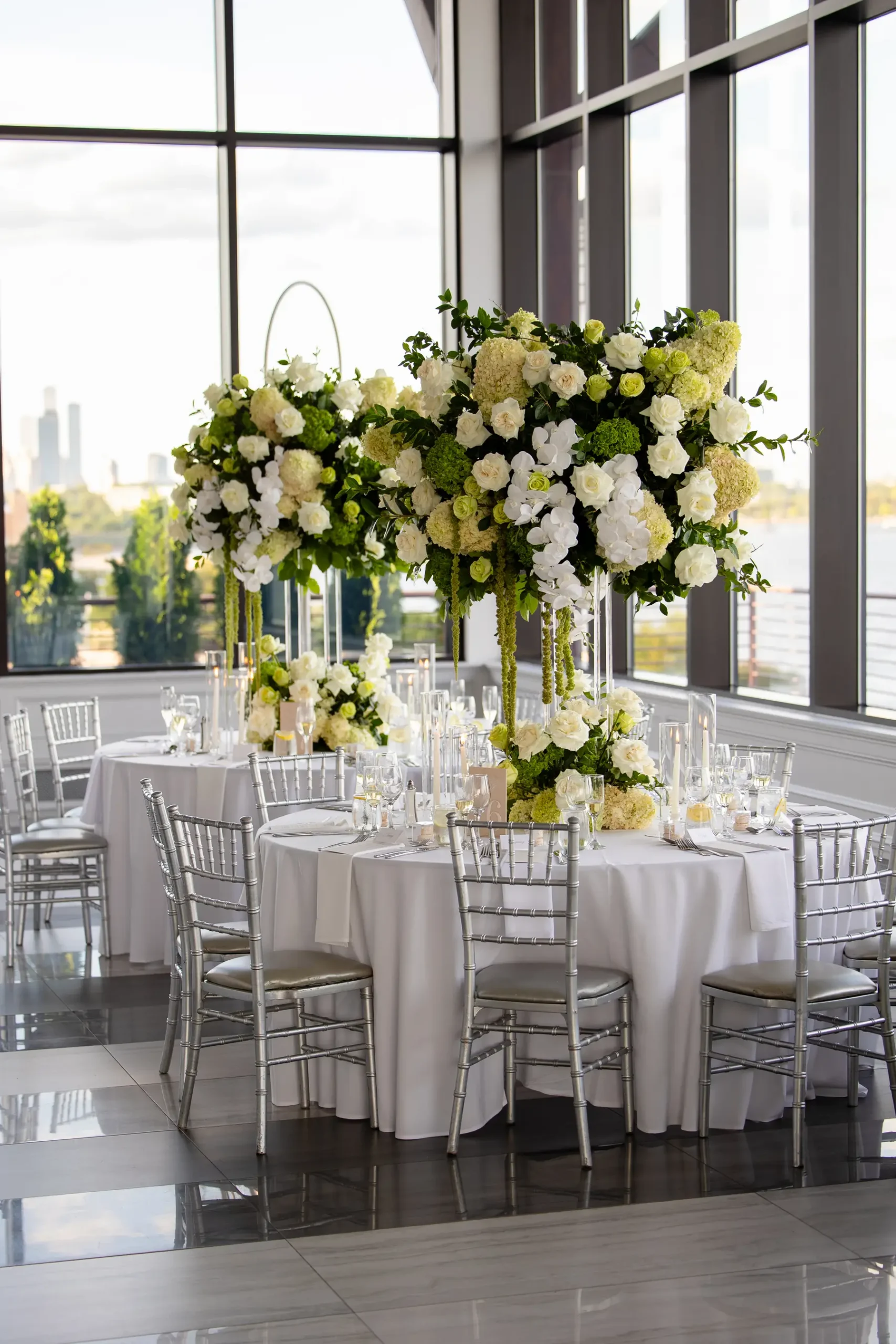 Tall white and green floral centerpiece on white-draped reception table at Hudson House in Jersey City, N.J.
