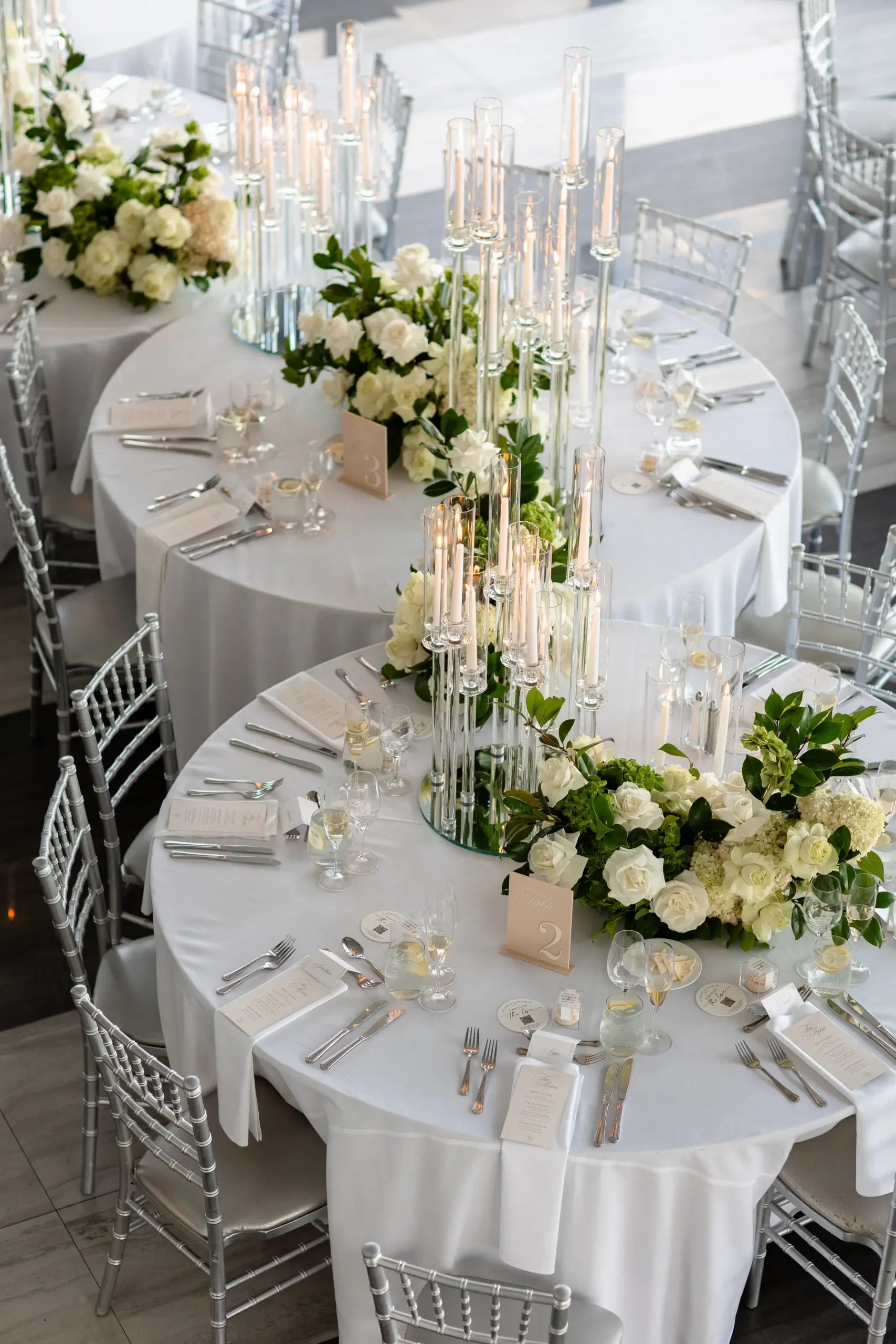 Elegant round reception tables with white floral centerpieces and tall glass candelabras at Hudson House in Jersey City.