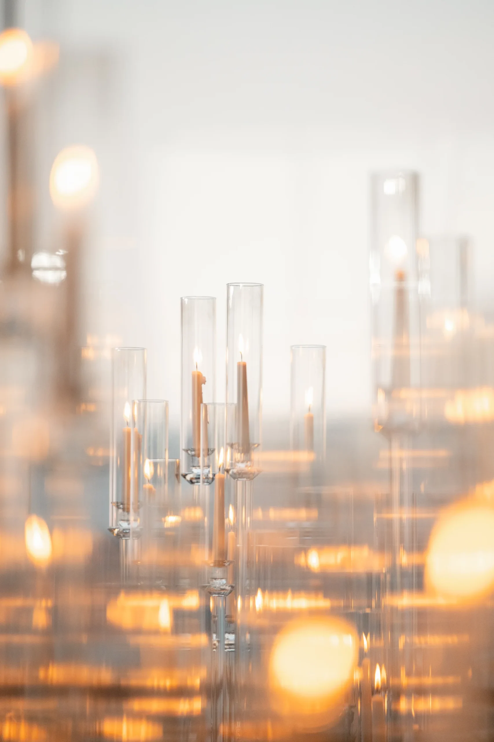 Tall glass hurricane candle holders with lit taper candles glow warmly at Katherine and Michelle's Hudson House wedding.