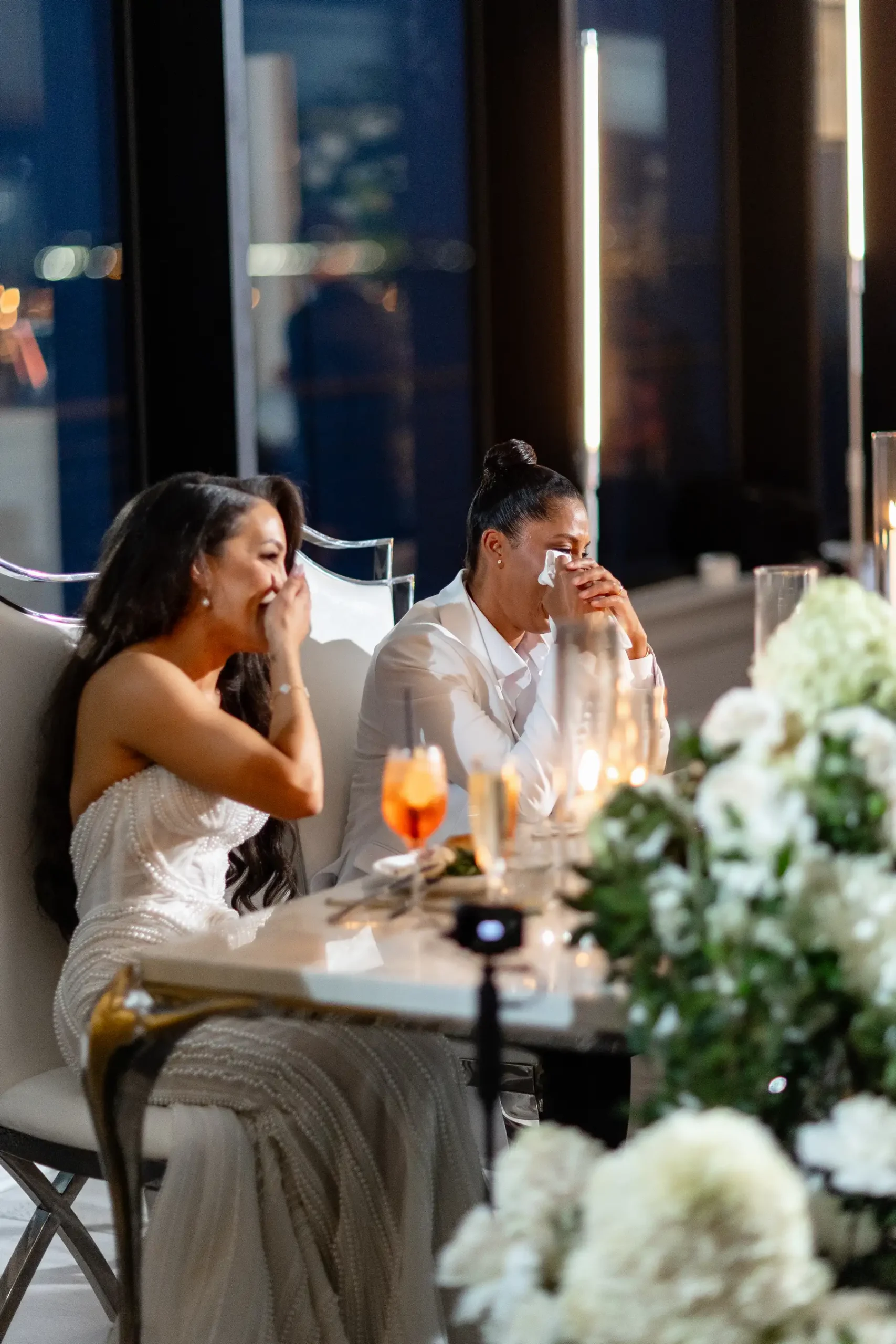 Brides Katherine and Michelle cry happy tears at their sweetheart table during their wedding reception at Hudson House in Jersey City.