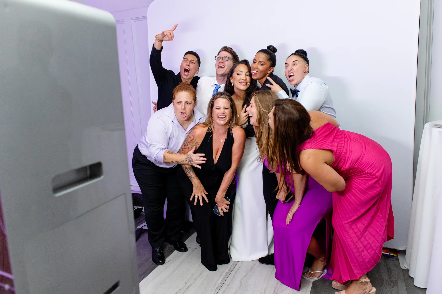 Guests and wedding party pose excitedly at a photo booth during Katherine and Michelle's reception at Hudson House in Jersey City.