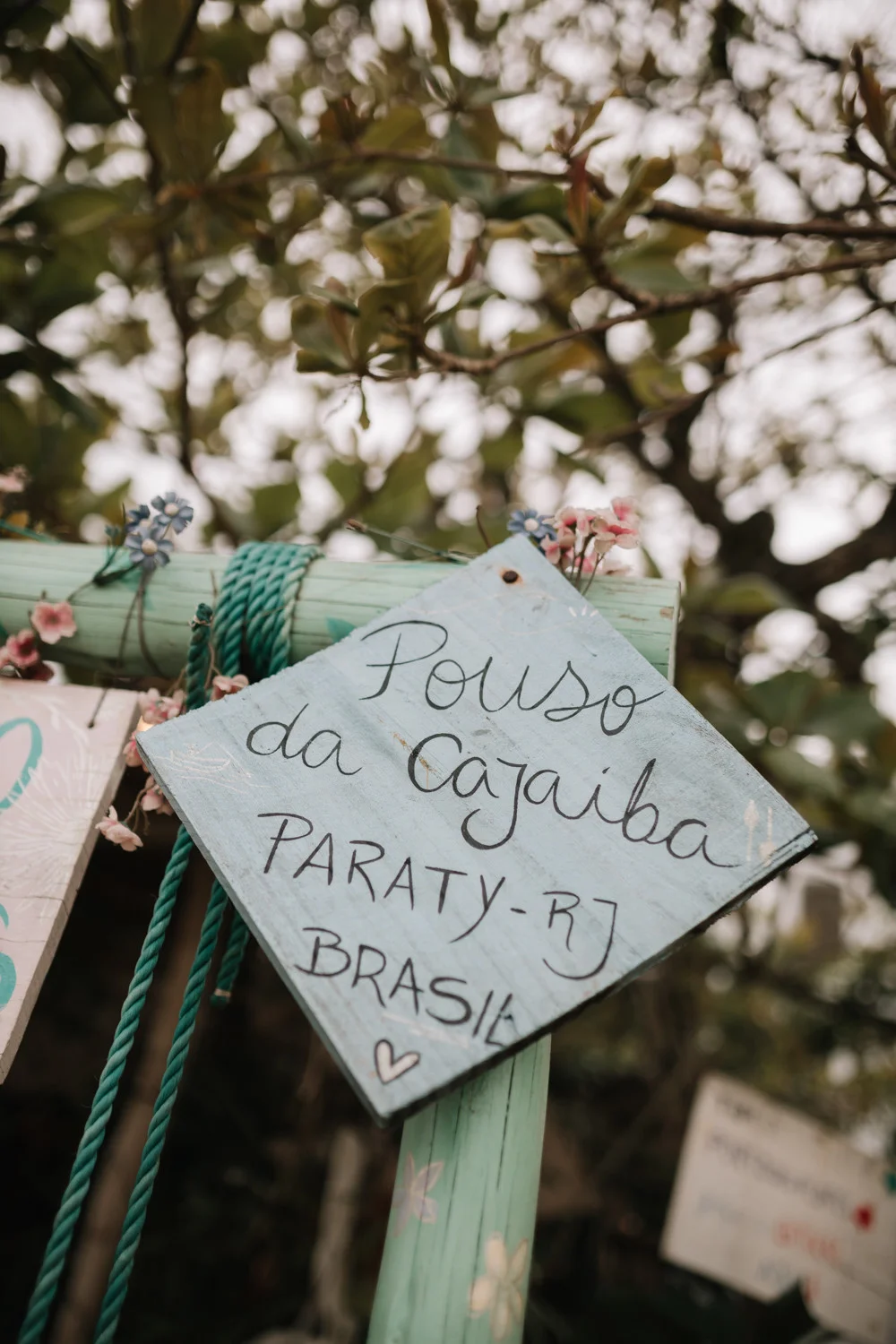 Handpainted wooden sign reading Pouso da Cajaiba, Paraty-RJ, Brasil at Rafaela and Nathalia's wedding.