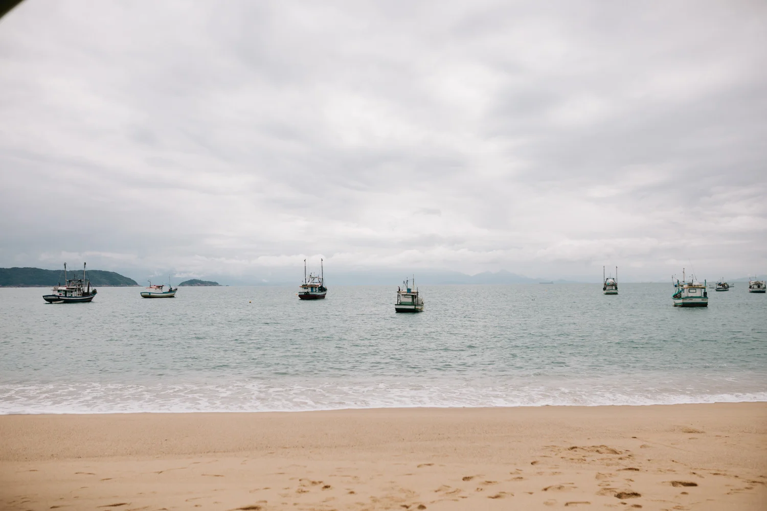 Fishing boats anchored in calm bay waters off the beach at Pouso das Flores in Paraty, Brazil.