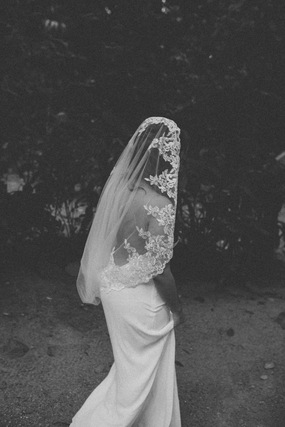 Bride in a sleek white gown and lace-trimmed veil draped over her face at Pouso das Flores in Paraty, Brazil.