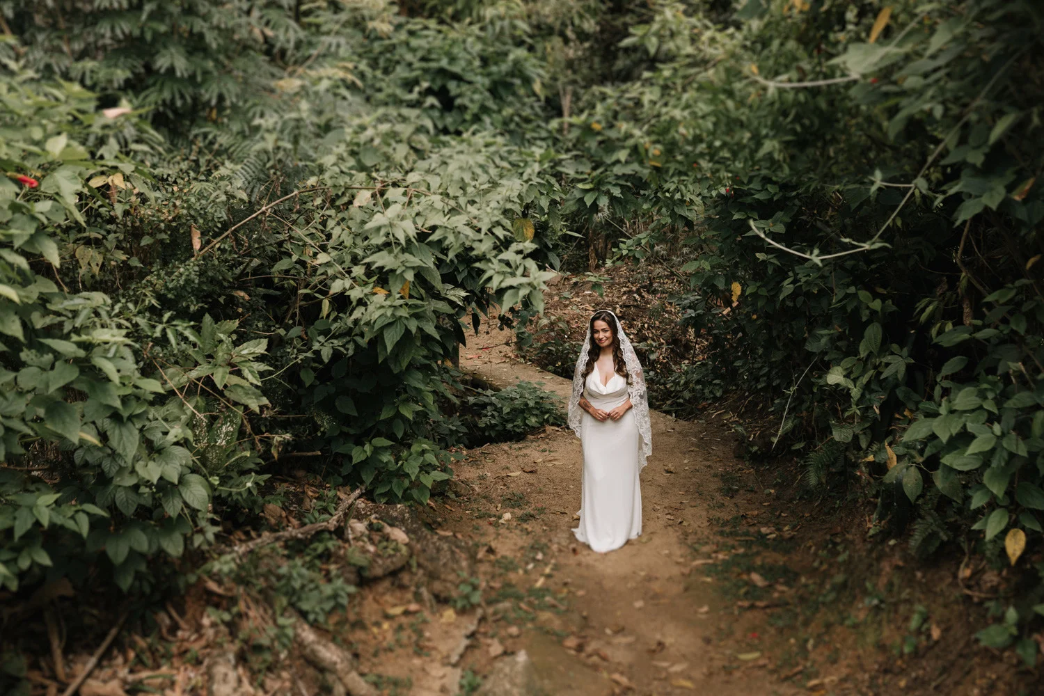 Bride Rafaela walks a lush jungle path in a white gown and lace veil at Pouso das Flores in Paraty, Brazil.