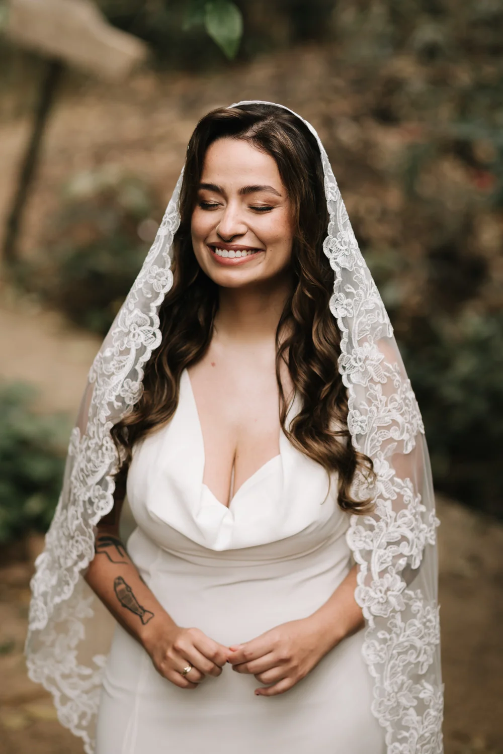 Bride Rafaela smiles with eyes closed in a white gown and lace veil at Pouso das Flores in Paraty, Brazil.
