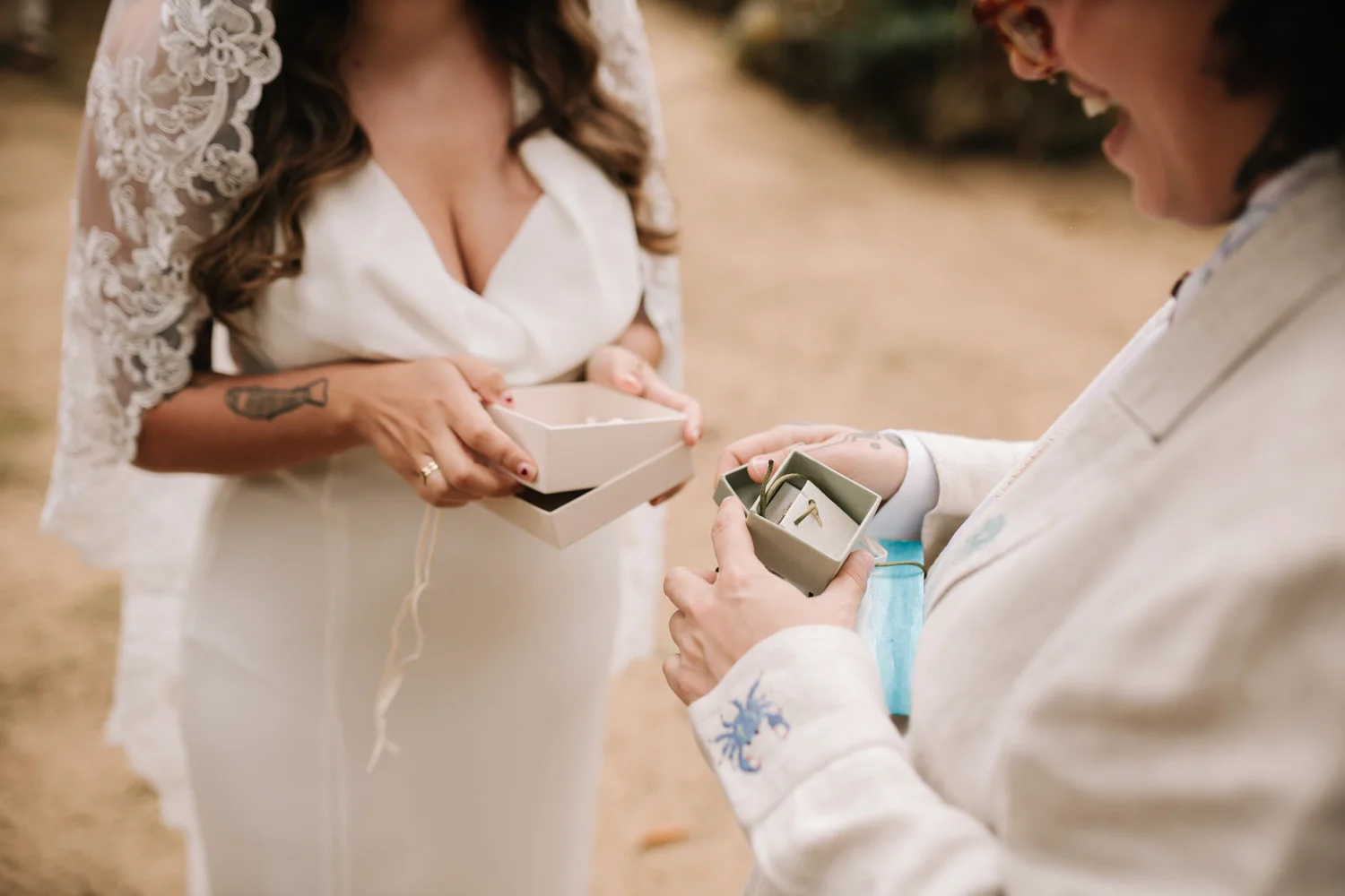 Rafaela and Nathalia exchange wedding ring boxes during their ceremony at Pouso das Flores in Paraty, Brazil.