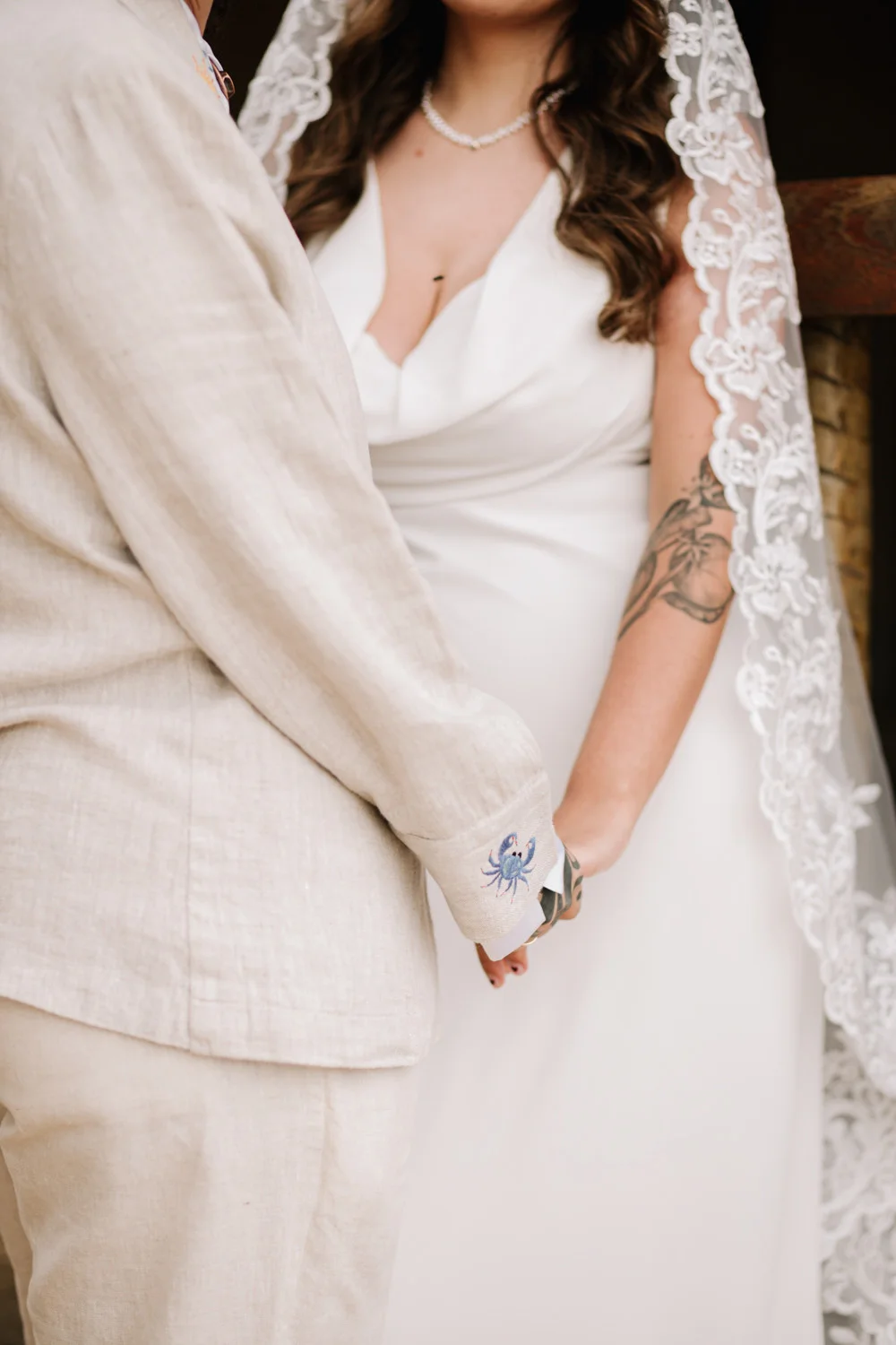 Rafaela and Nathalia hold hands at Pouso das Flores, showing a crab cuff detail and arm tattoos.
