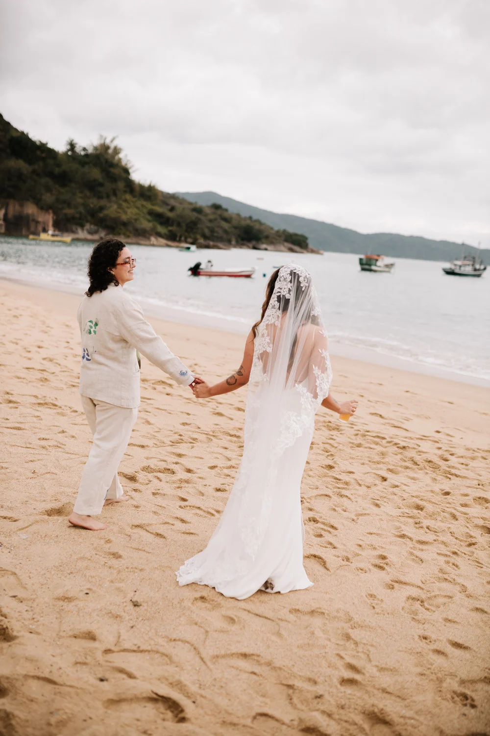 Rafaela and Nathalia walk hand in hand on the beach at Pouso das Flores in Paraty, Brazil.