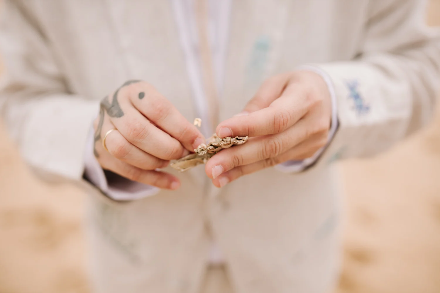 Hands holding a delicate gold shell chain bracelet at Pouso das Flores in Paraty, Brazil.