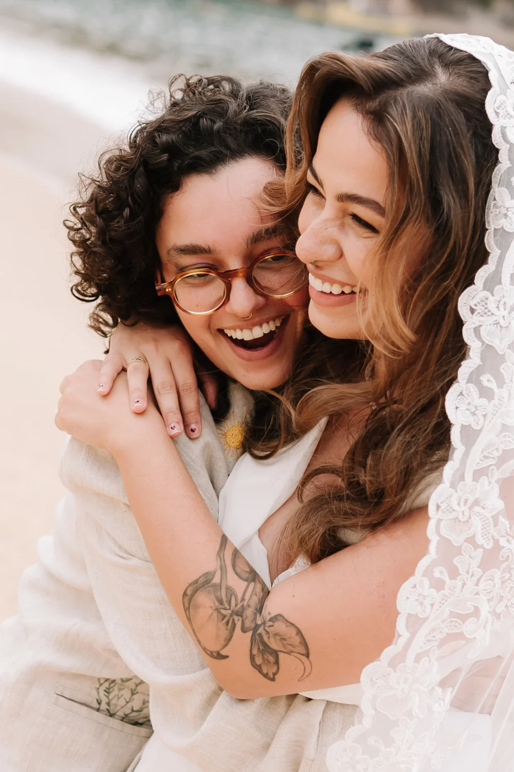 Rafaela and Nathalia laugh and embrace on the beach at Pouso das Flores in Paraty, Brazil.