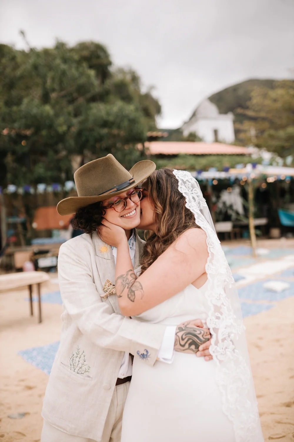 Rafaela and Nathalia embrace and share a tender kiss on the cheek at Pouso das Flores in Paraty, Brazil.