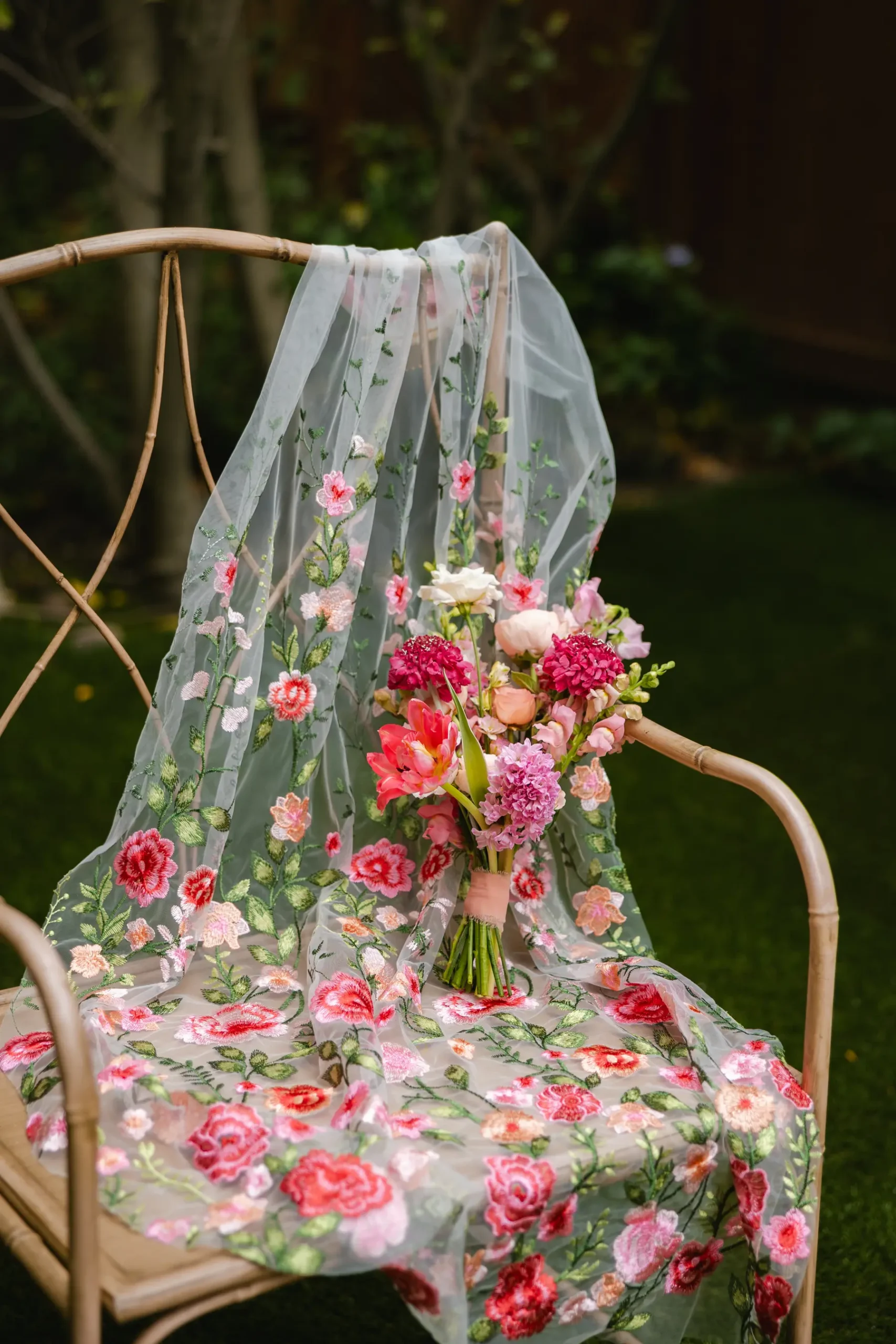 Floral embroidered veil and pink bouquet on a rattan chair at Botanica in Oceanside, California.