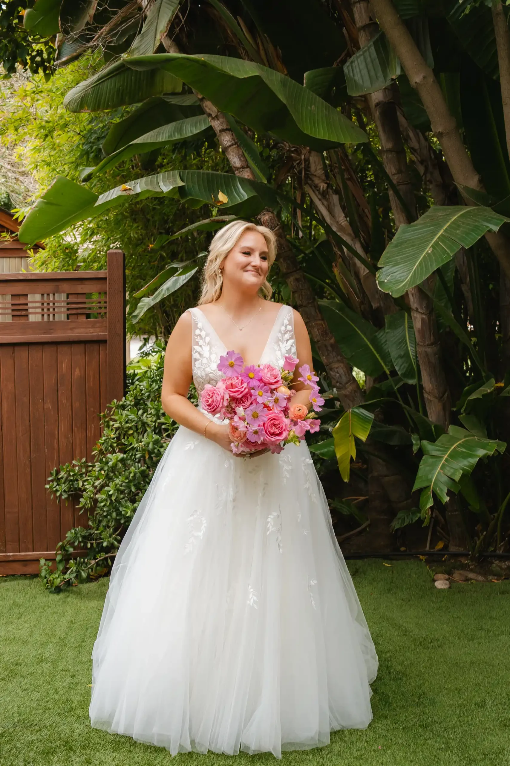 Bride in a white ball gown holds a pink bouquet at Botanica in Oceanside, California.
