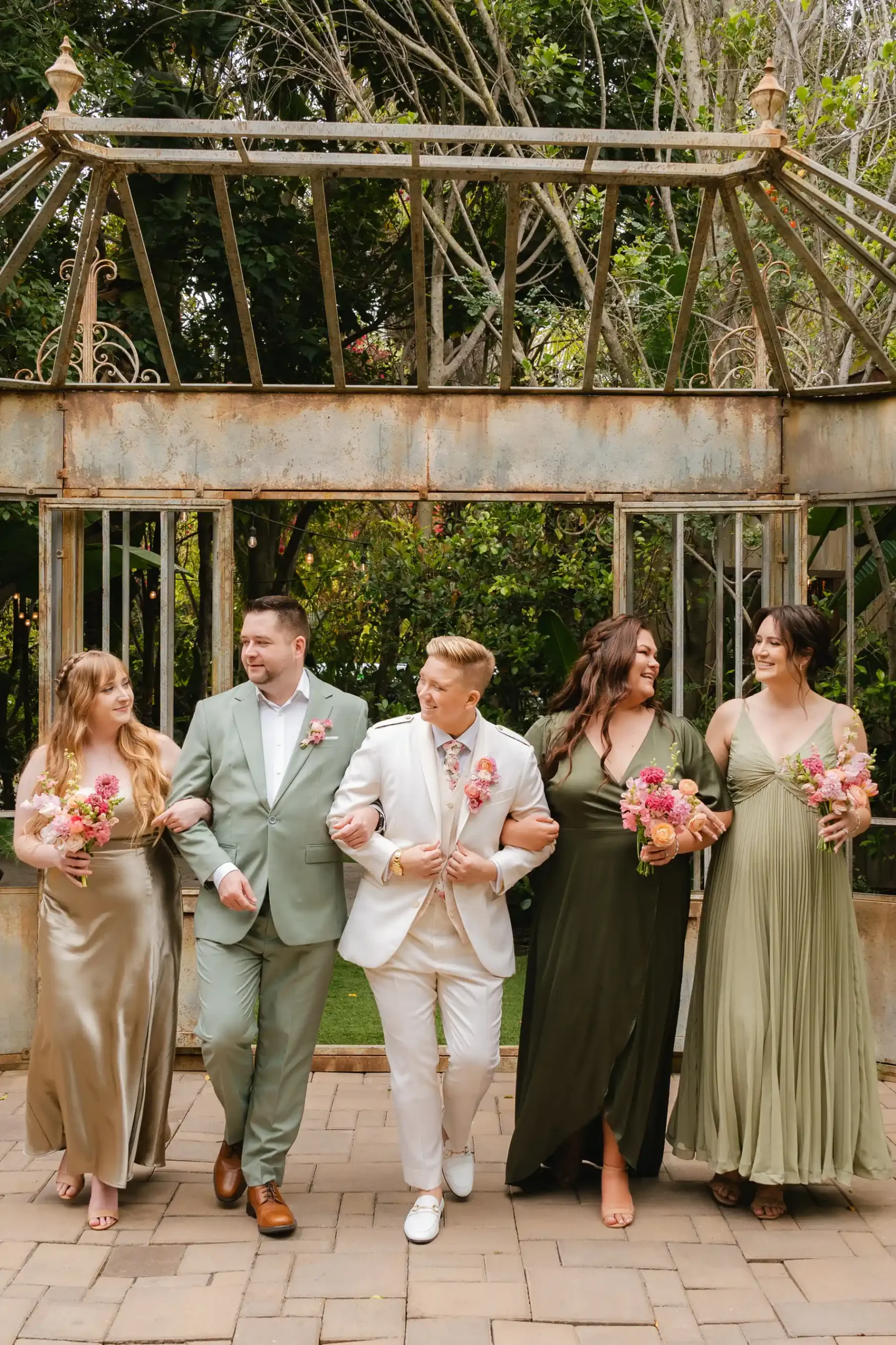 Brides Erika Beursken and Melissa Brodsky walk arm-in-arm with their wedding party at Botanica in Oceanside, California.