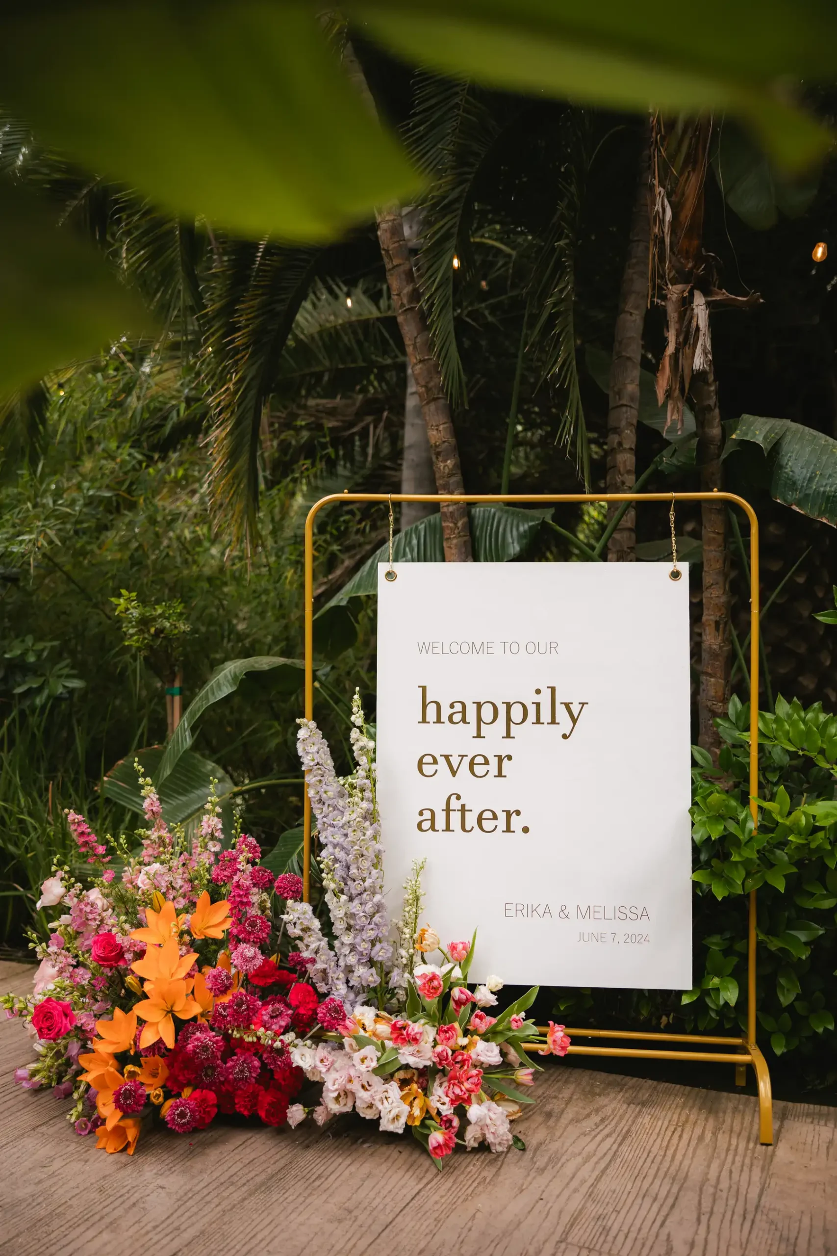 Wedding welcome sign reading 'happily ever after' for Erika and Melissa, June 7, 2024, surrounded by colorful florals at Botanica in Oceanside, California.
