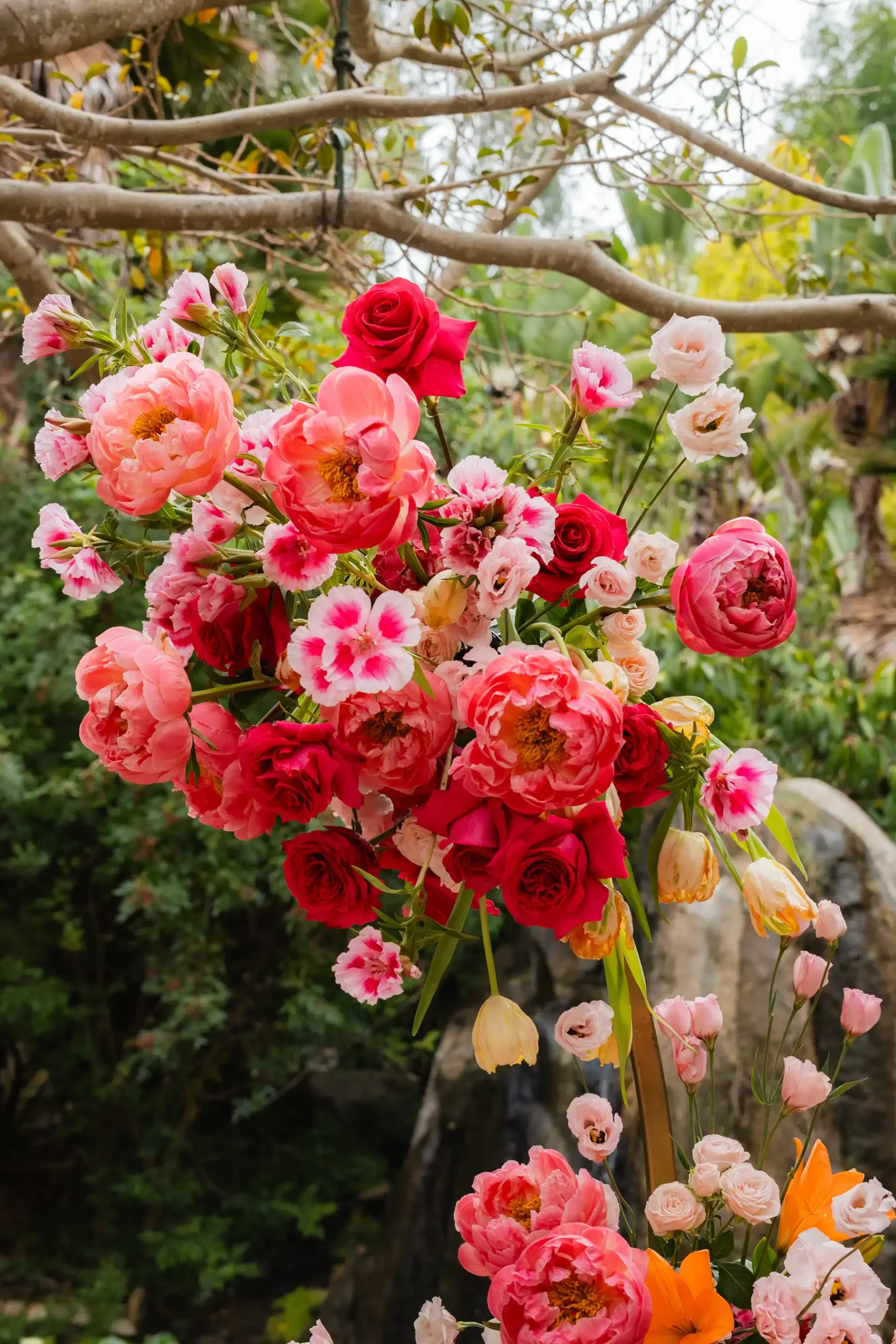 Lush floral arrangement of coral peonies, red roses and pink lisianthus at Botanica in Oceanside, California.