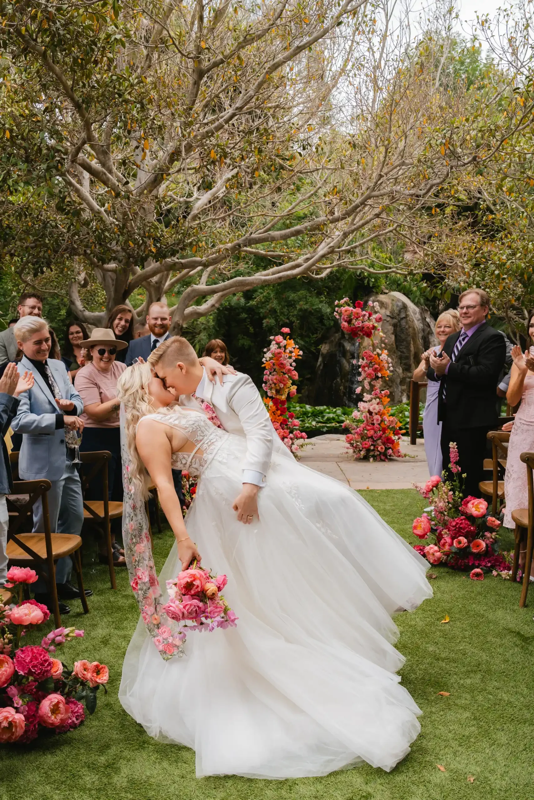 Erika Beursken and Melissa Brodsky share a dip kiss while walking the aisle at Botanica in Oceanside, California.