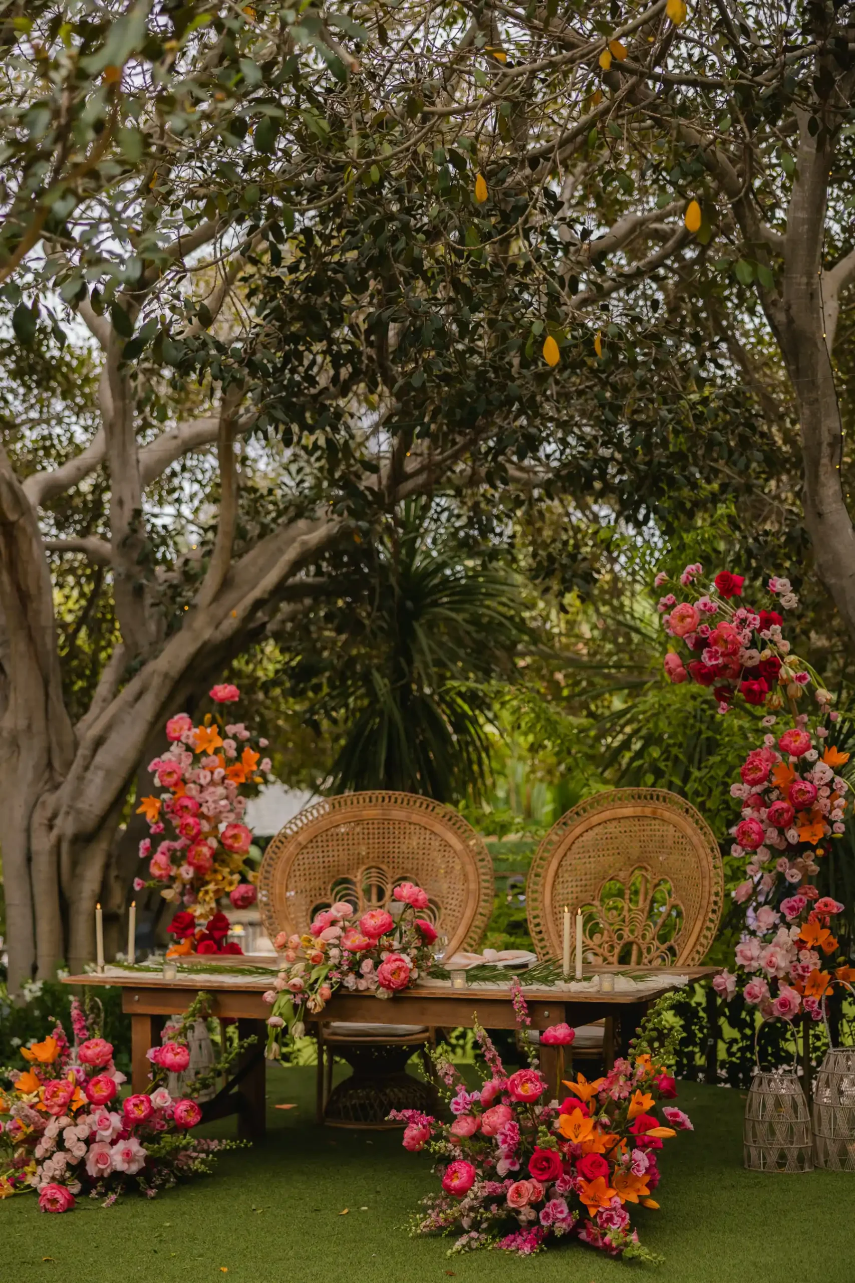 Sweetheart table with peacock chairs and vibrant pink, orange and red florals at Botanica in Oceanside, California.