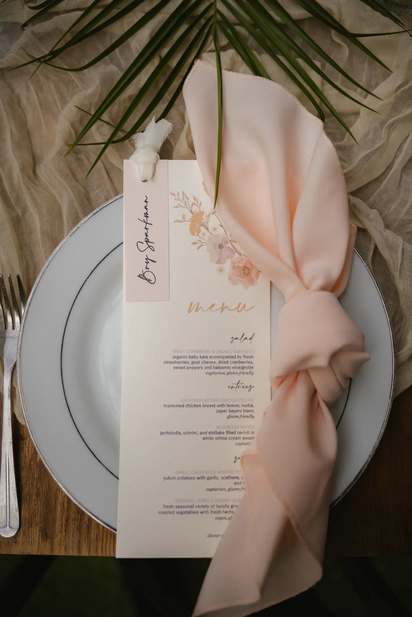 Elegant floral menu card and blush napkin at Erika Beursken and Melissa Brodsky's wedding at Botanica in Oceanside, California.