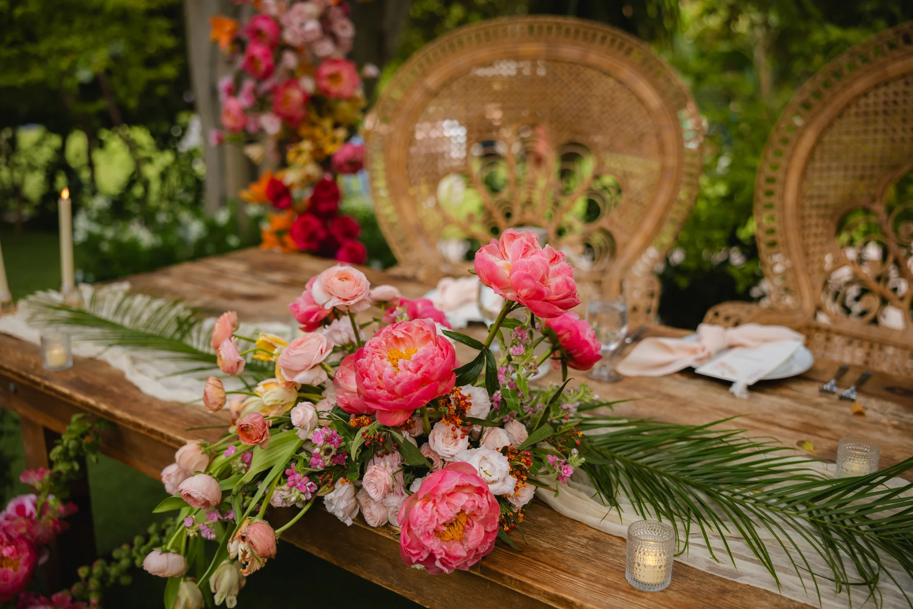Lush pink peony and garden rose centerpiece on a wooden farm table at Botanica in Oceanside, California.