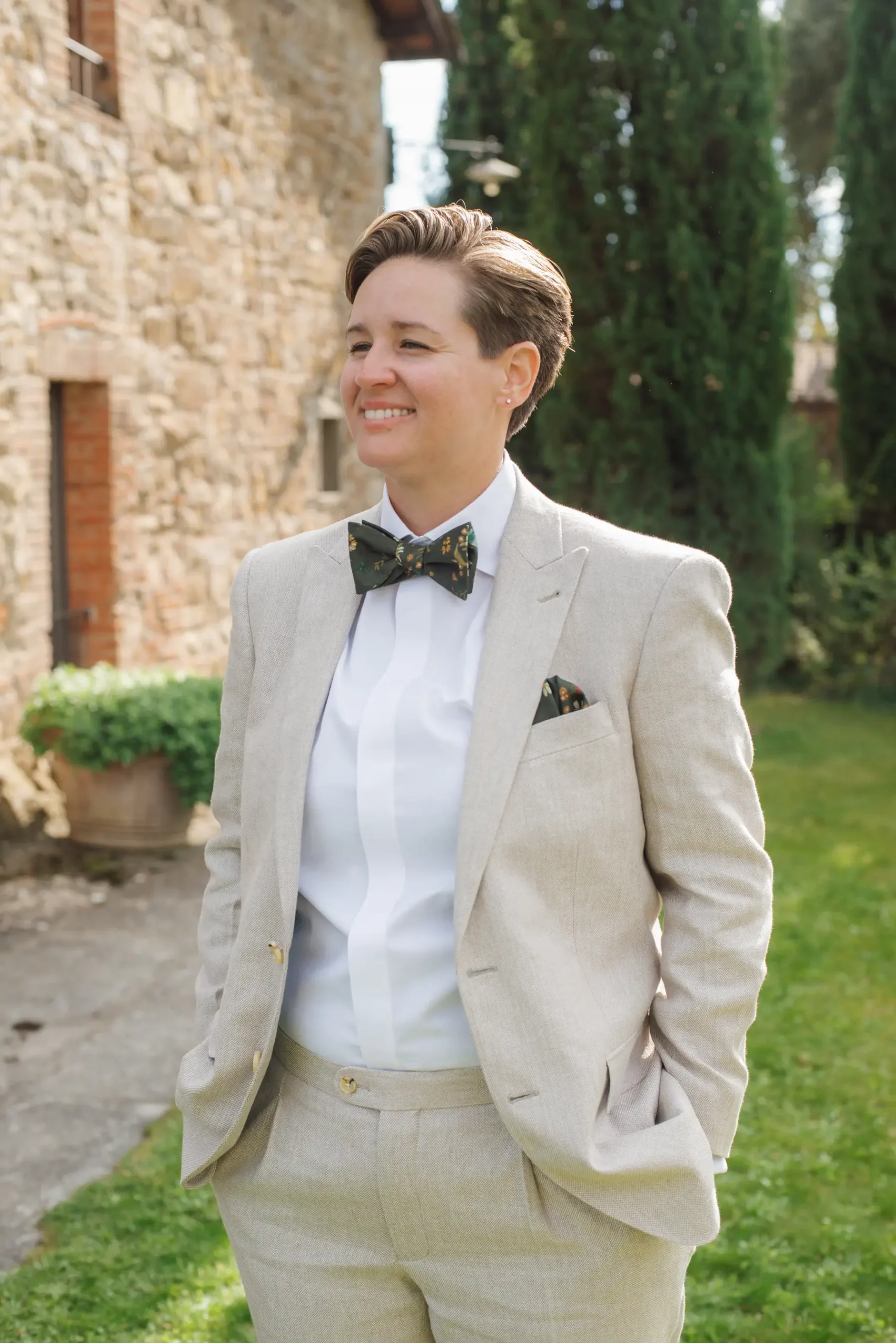 Lauren Thomas smiles in a linen suit and floral bow tie at Casa Cornacchi in Arezzo, Tuscany, Italy.