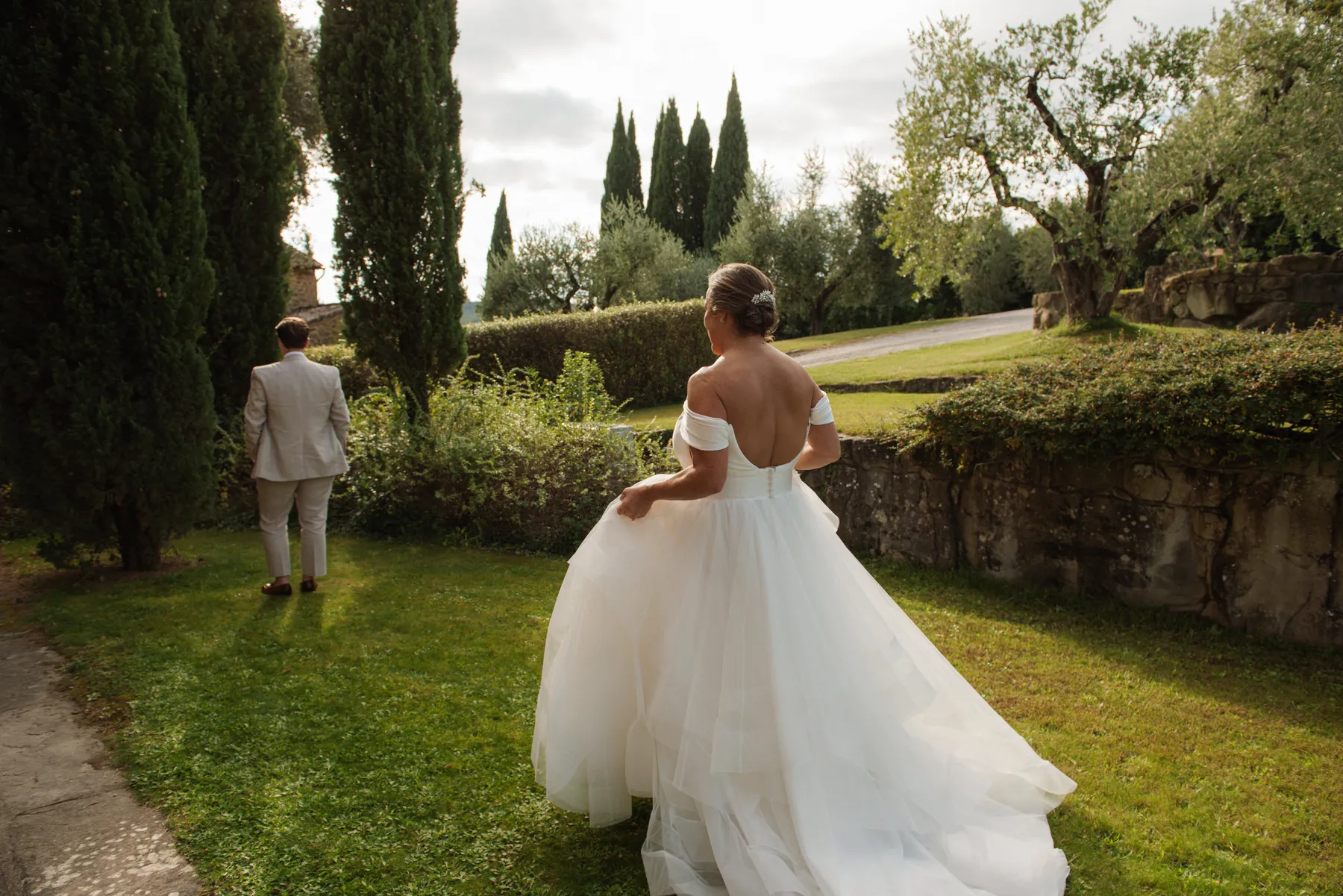 Bride Lauren Thomas walks toward groom in a lush garden at Casa Cornacchi in Arezzo, Tuscany, Italy.