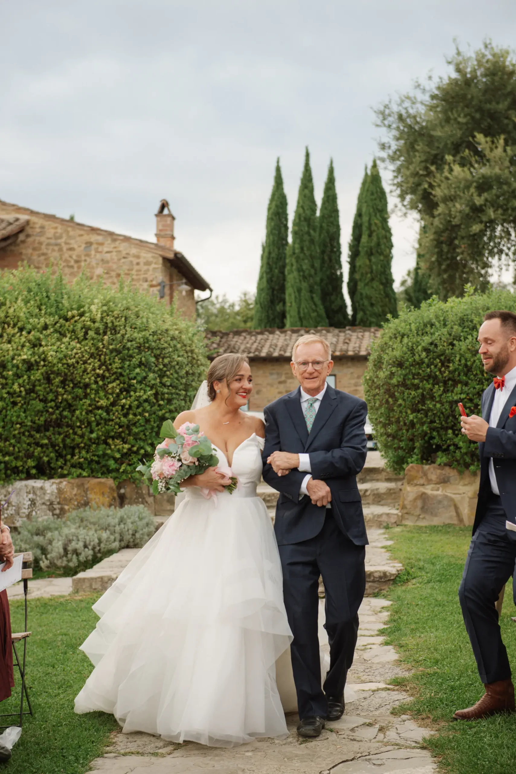 Lauren Thomas walks down the aisle with an escort at Casa Cornacchi in Arezzo, Tuscany, Italy.