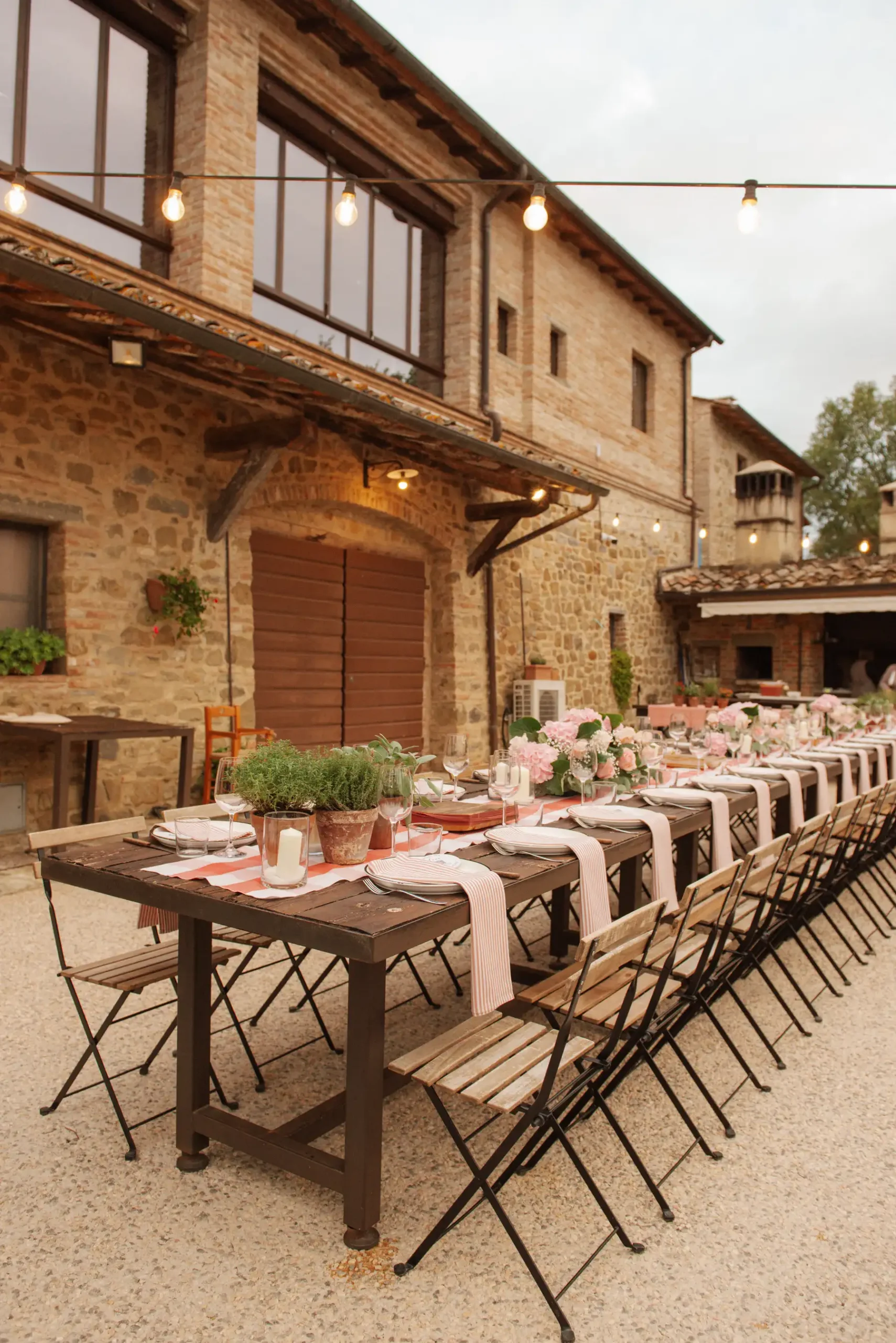 Long outdoor dining table set for Lauren Thomas and Jasmine Shimerda's reception at Casa Cornacchi in Tuscany, Italy.