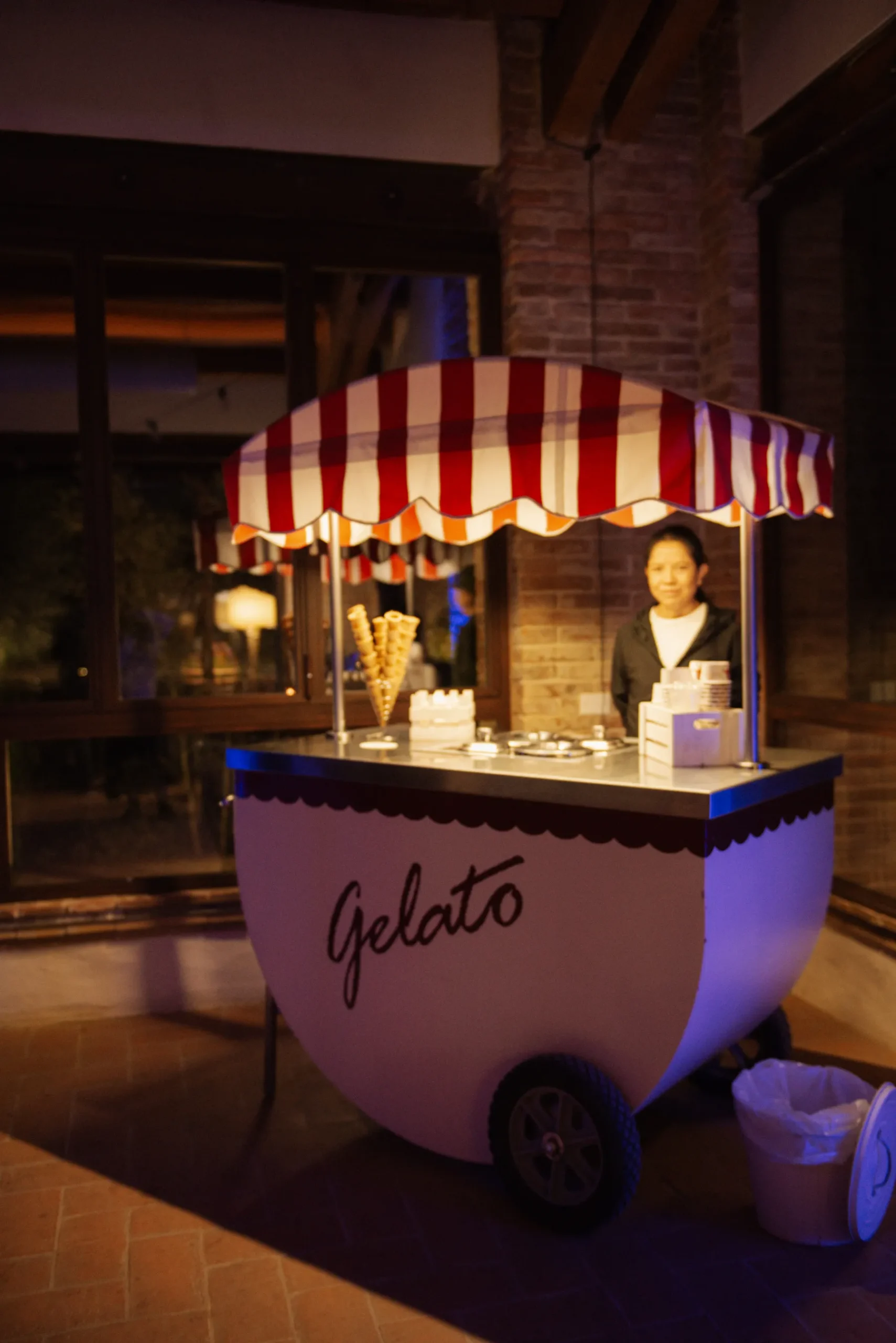 A gelato cart with a red-and-white striped awning at Lauren and Jasmine's wedding reception at Casa Cornacchi in Tuscany.