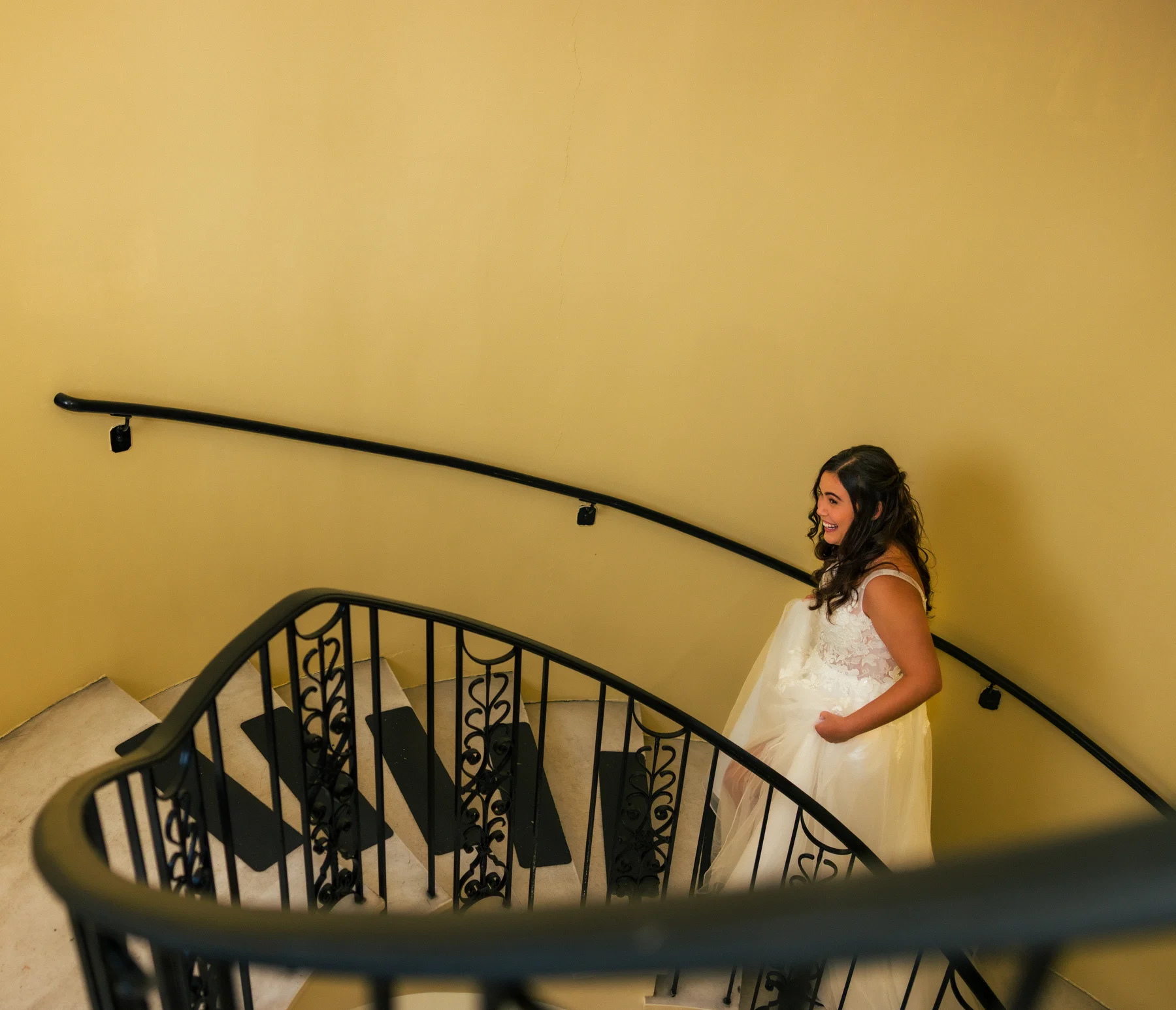 Bride Stephanie Tillman walks up a spiral staircase in a white lace gown at Hampshire House in Boston.