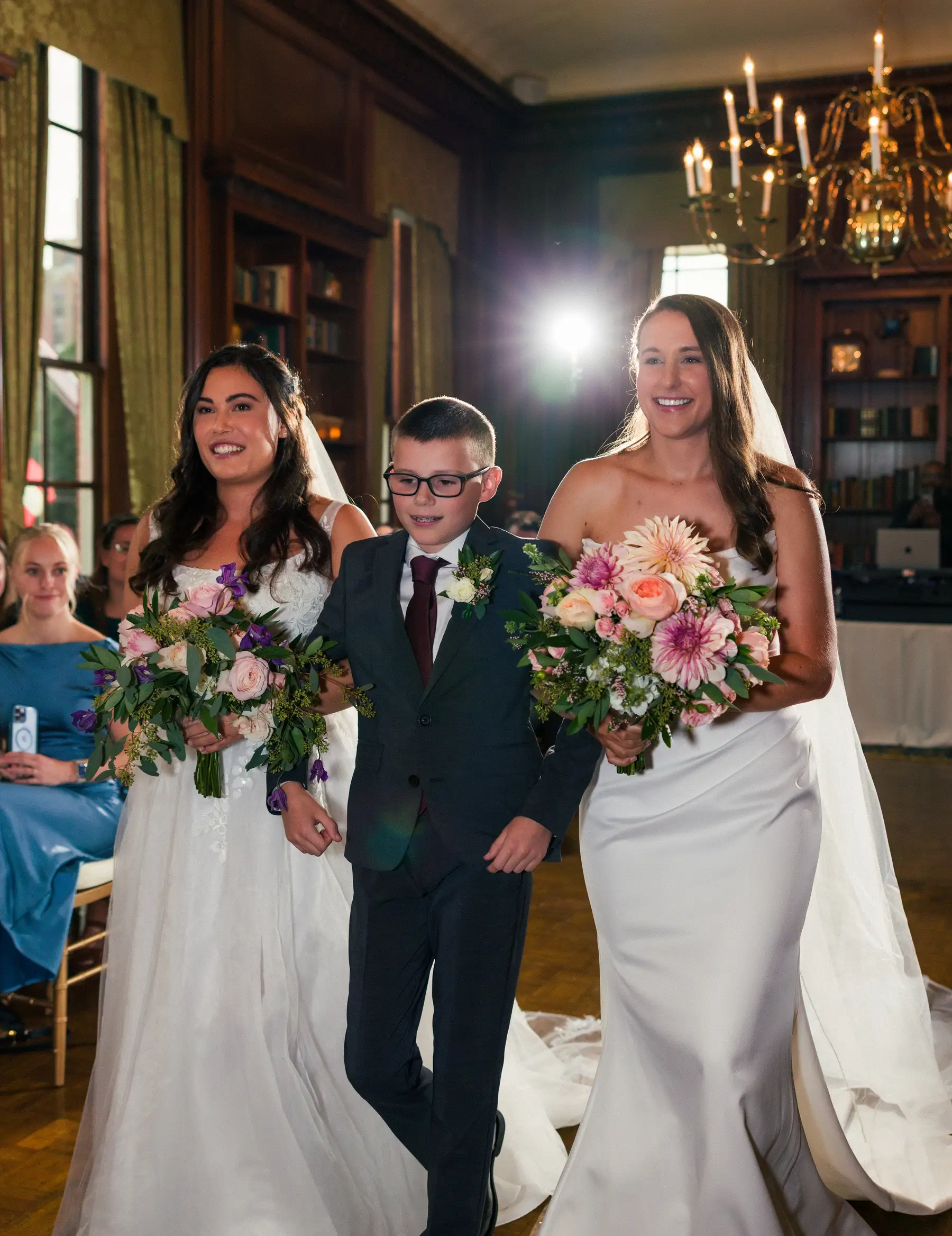 Brides Ashton Hattori and Stephanie Tillman walk the aisle with a young escort at Hampshire House in Boston.
