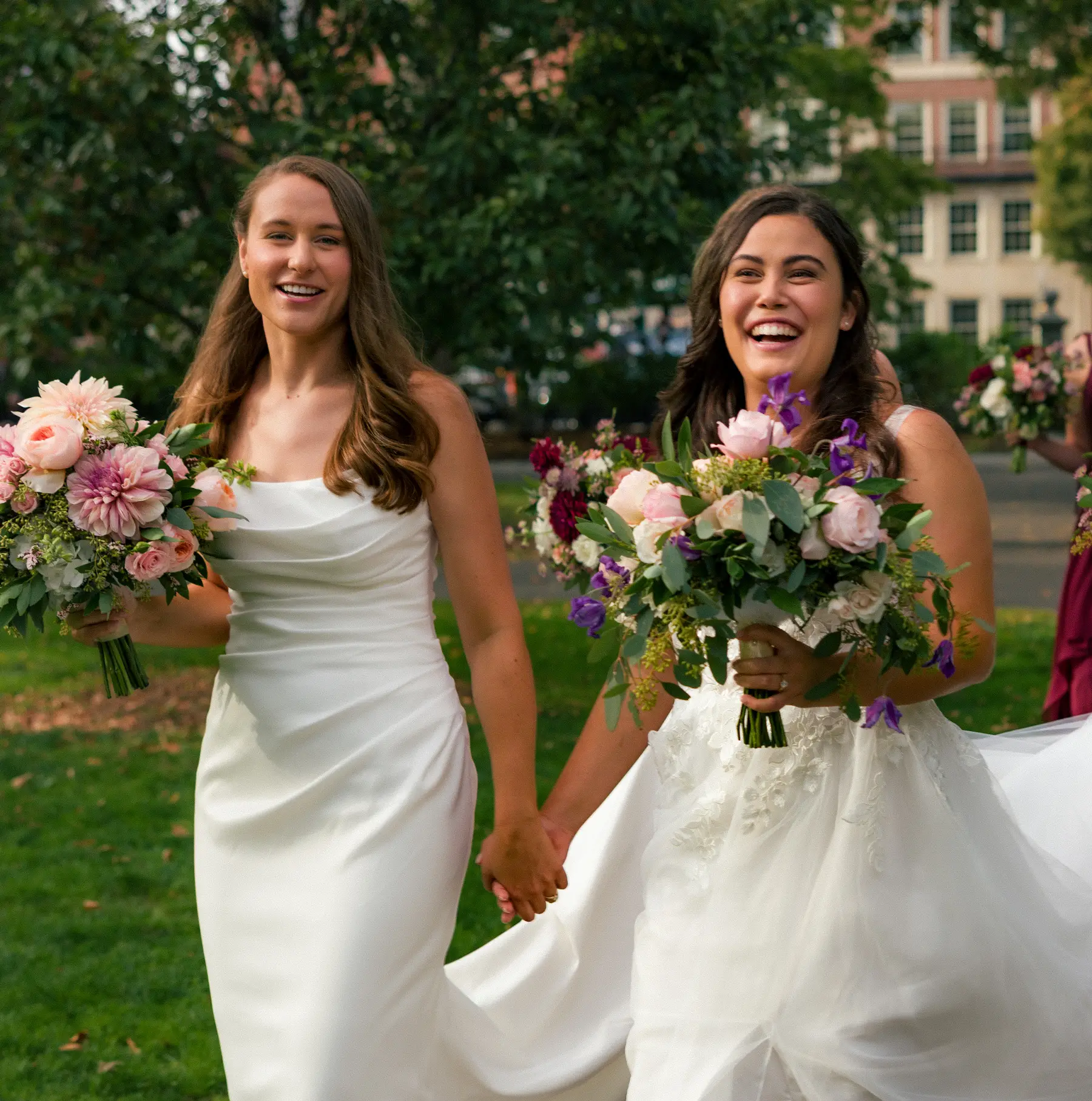 Brides Ashton Hattori and Stephanie Tillman walk hand in hand laughing in white gowns at Hampshire House in Boston.