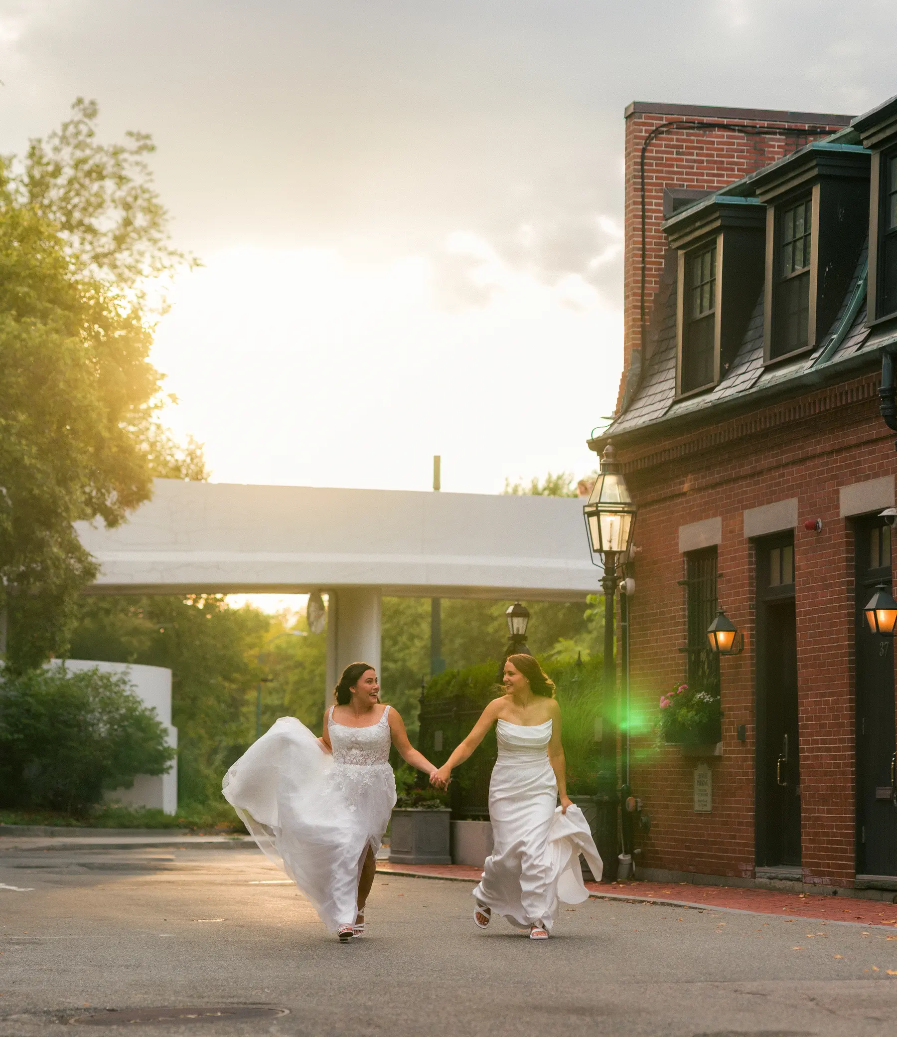 Brides Ashton Hattori and Stephanie Tillman hold hands and run in white gowns outside Hampshire House in Boston.