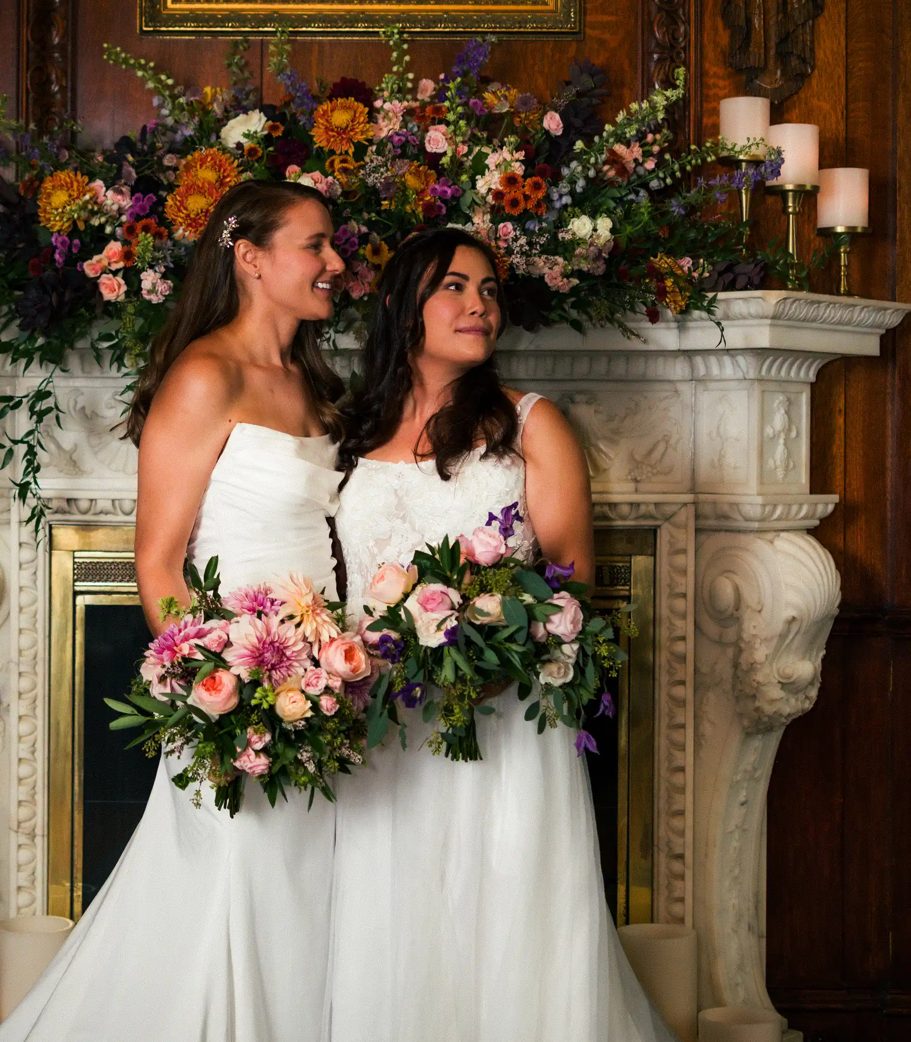 Brides Ashton Hattori and Stephanie Tillman hold floral bouquets before an ornate fireplace at Hampshire House in Boston.