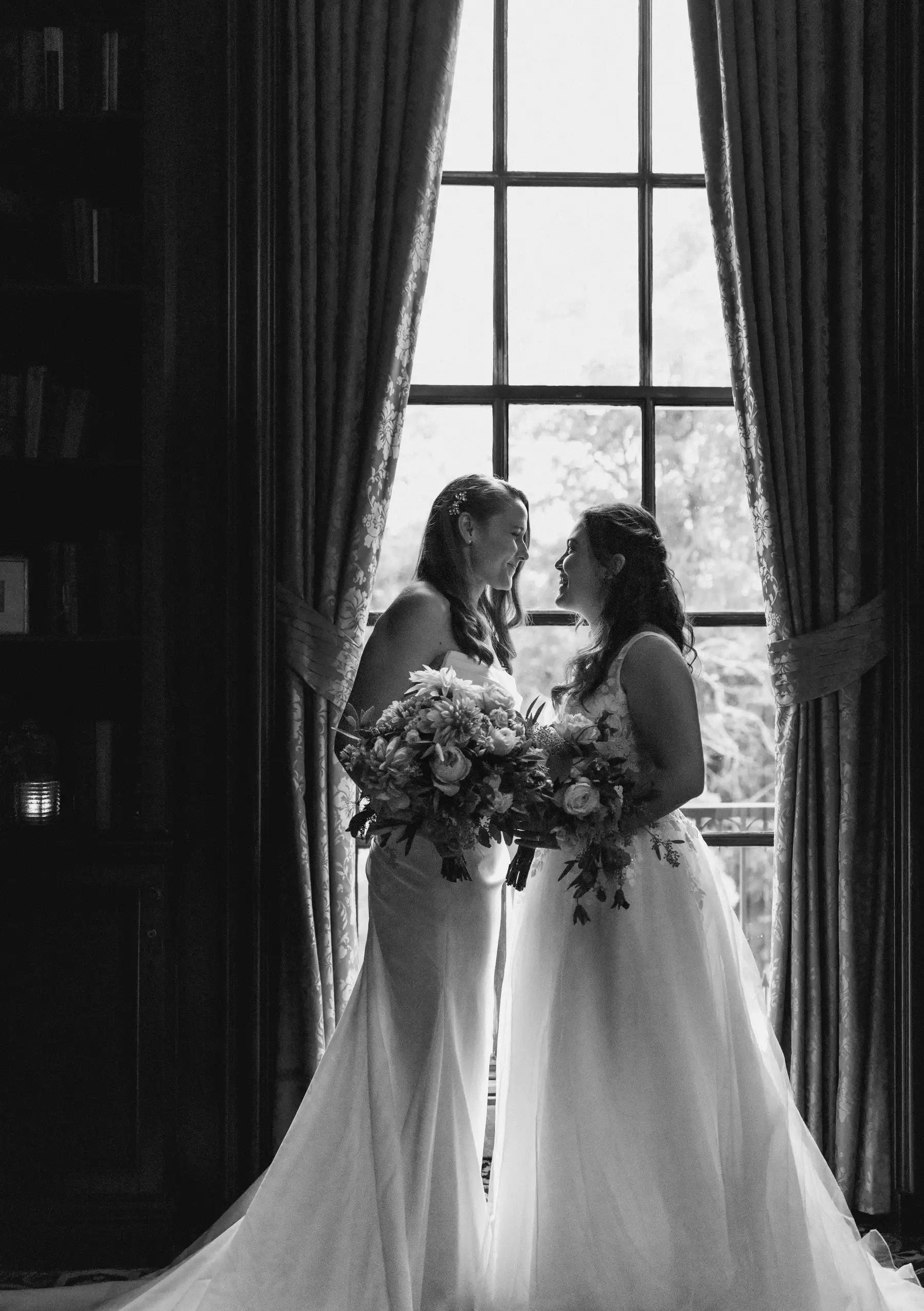Brides Ashton Hattori and Stephanie Tillman share a joyful moment in wedding gowns at Hampshire House, Boston.