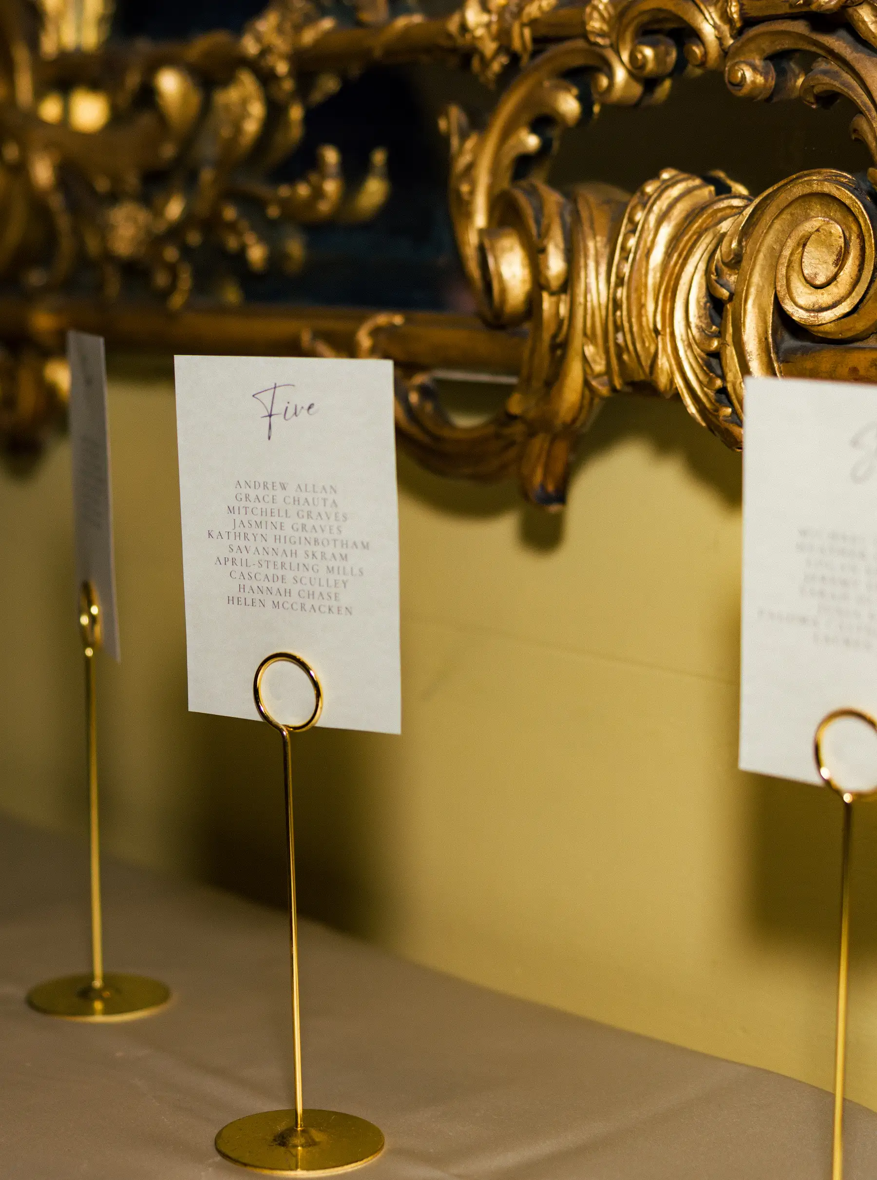 Gold table card holders display seating chart for Table Five at Ashton Hattori and Stephanie Tillman's wedding at Hampshire House, Boston.