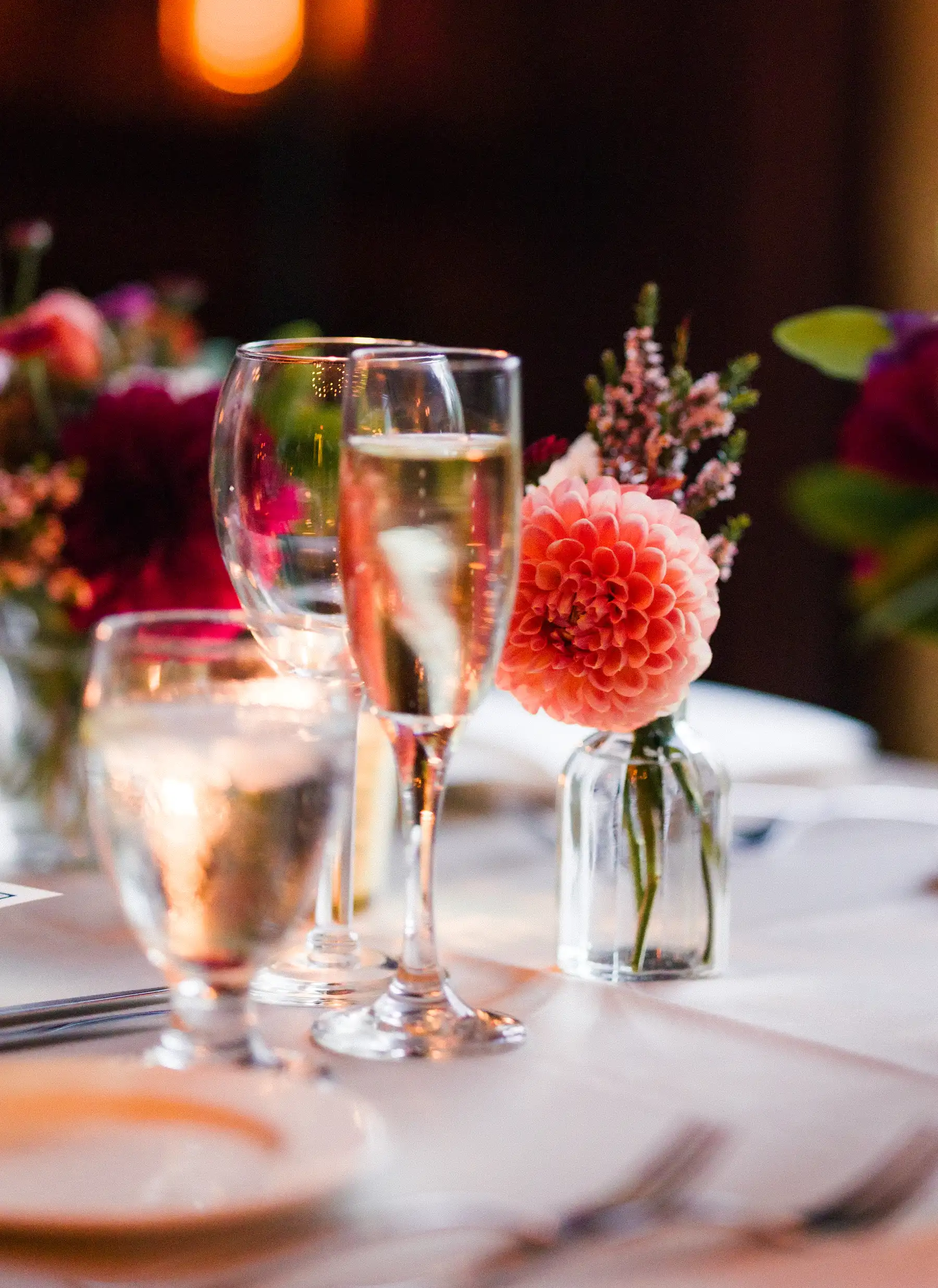 Champagne flutes and a coral dahlia in a bud vase adorn a reception table at Hampshire House in Boston.