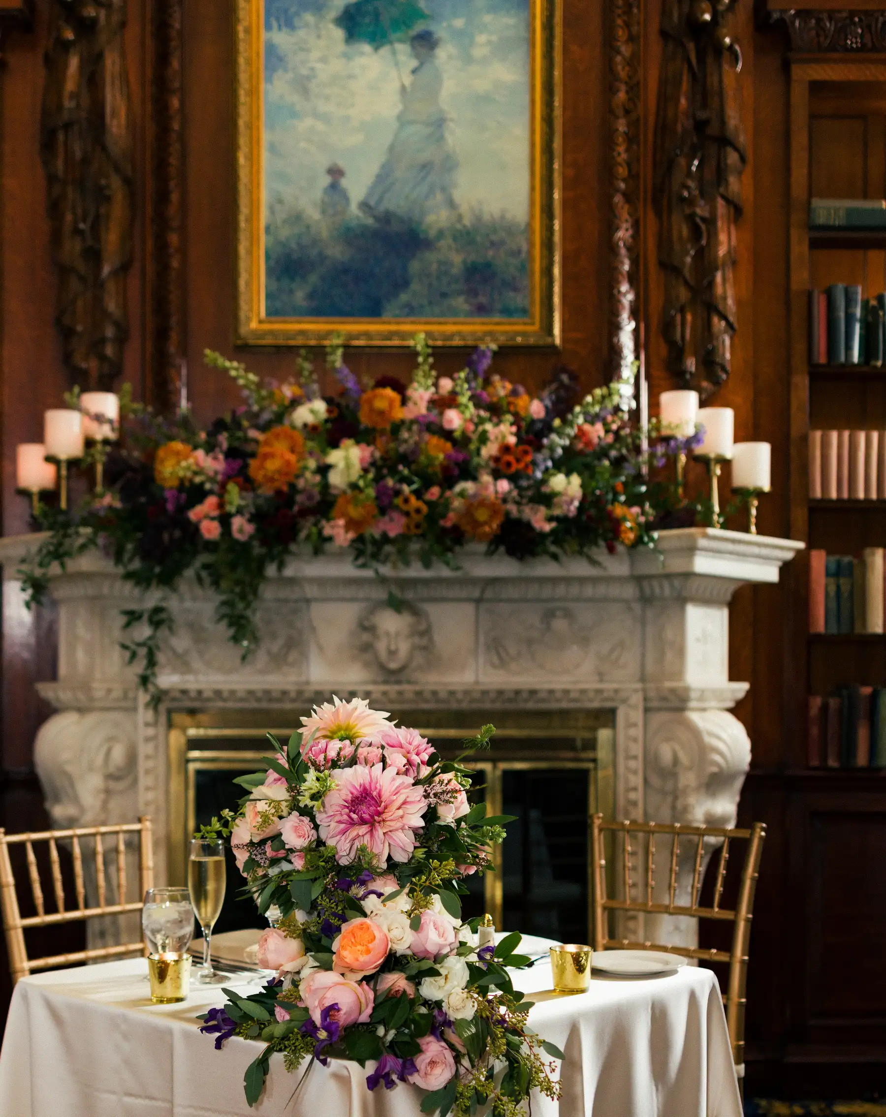 Lush floral centerpiece with pink dahlias and roses on sweetheart table before ornate fireplace at Hampshire House, Boston.